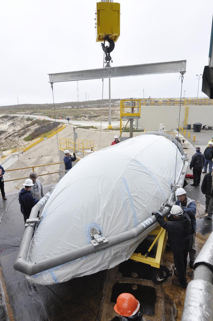 VANDENBERG AIR FORCE BASE, Calif. – A half section of the 10-foot-diameter fairing for NASA's Soil Moisture Active Passive mission, or SMAP, is attached to a crane during preparations to hoist it into the environmental enclosure at the top of the mobile service tower at Space Launch Complex 2 on Vandenberg Air Force Base in California.    The fairing will protect the SMAP spacecraft from the heat and aerodynamic pressure generated during its ascent to orbit aboard a United Launch Alliance Delta II rocket. SMAP will provide global measurements of soil moisture and its freeze/thaw state. These measurements will be used to enhance understanding of processes that link the water, energy and carbon cycles, and to extend the capabilities of weather and climate prediction models. SMAP data will also be used to quantify net carbon flux in boreal landscapes and to develop improved flood prediction and drought monitoring capabilities. Launch is scheduled for no earlier than November 2014. To learn more about SMAP, visit http://smap.jpl.nasa.gov.  Photo credit: NASA/Randy Beaudoin