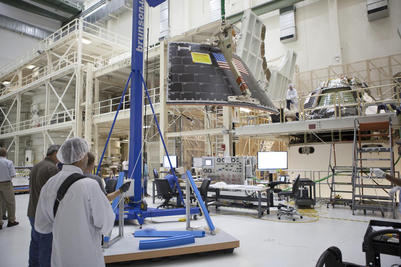 CAPE CANAVERAL, Fla. – Inside the Operations and Checkout Building high bay at NASA's Kennedy Space Center in Florida, technicians and engineers monitor the progress as a crane is used to lift the middle back shell tile panel for installation on the Orion crew module. Preparations are underway for Exploration Flight Test-1, or EFT-1. Orion is the exploration spacecraft designed to carry astronauts to destinations not yet explored by humans, including an asteroid and Mars. It will have emergency abort capability, sustain the crew during space travel and provide safe re-entry from deep space return velocities. The first unpiloted test flight of the Orion is scheduled to launch later this year atop a Delta IV rocket from Cape Canaveral Air Force Station in Florida to an altitude of 3,600 miles above the Earth's surface. The two-orbit, four-hour flight test will help engineers evaluate the systems critical to crew safety including the heat shield, parachute system and launch abort system. For more information, visit http://www.nasa.gov/orion. Photo credit: NASA/Dimitri Gerondidakis