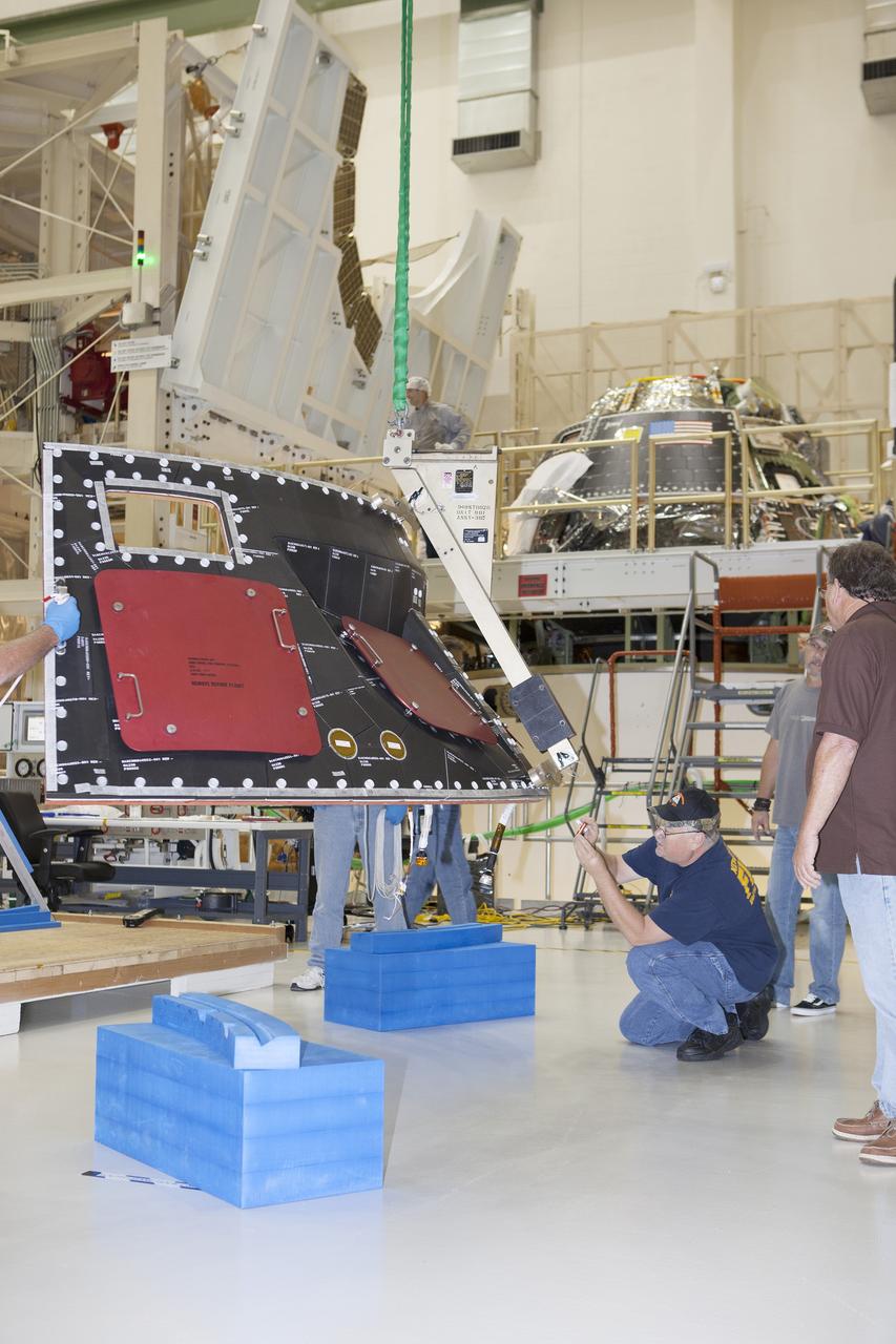 CAPE CANAVERAL, Fla. – Inside the Operations and Checkout Building high bay at NASA's Kennedy Space Center in Florida, technicians and engineers monitor the progress as a crane is used to lift the middle back shell tile panel for installation on the Orion crew module. Preparations are underway for Exploration Flight Test-1, or EFT-1. Orion is the exploration spacecraft designed to carry astronauts to destinations not yet explored by humans, including an asteroid and Mars. It will have emergency abort capability, sustain the crew during space travel and provide safe re-entry from deep space return velocities. The first unpiloted test flight of the Orion is scheduled to launch later this year atop a Delta IV rocket from Cape Canaveral Air Force Station in Florida to an altitude of 3,600 miles above the Earth's surface. The two-orbit, four-hour flight test will help engineers evaluate the systems critical to crew safety including the heat shield, parachute system and launch abort system. For more information, visit http://www.nasa.gov/orion. Photo credit: NASA/Dimitri Gerondidakis