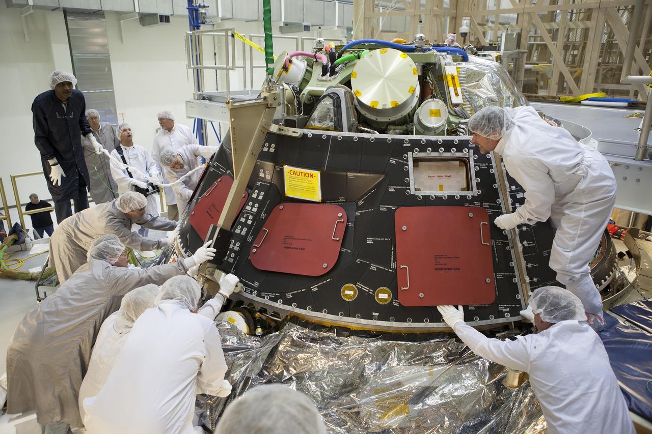 CAPE CANAVERAL, Fla. – Inside the Operations and Checkout Building high bay at NASA's Kennedy Space Center in Florida, technicians dressed in clean-room suits line up the middle back shell tile panel for installation on the Orion crew module. Preparations are underway for Exploration Flight Test-1, or EFT-1. Orion is the exploration spacecraft designed to carry astronauts to destinations not yet explored by humans, including an asteroid and Mars. It will have emergency abort capability, sustain the crew during space travel and provide safe re-entry from deep space return velocities. The first unpiloted test flight of the Orion is scheduled to launch later this year atop a Delta IV rocket from Cape Canaveral Air Force Station in Florida to an altitude of 3,600 miles above the Earth's surface. The two-orbit, four-hour flight test will help engineers evaluate the systems critical to crew safety including the heat shield, parachute system and launch abort system. For more information, visit http://www.nasa.gov/orion. Photo credit: NASA/Dimitri Gerondidakis