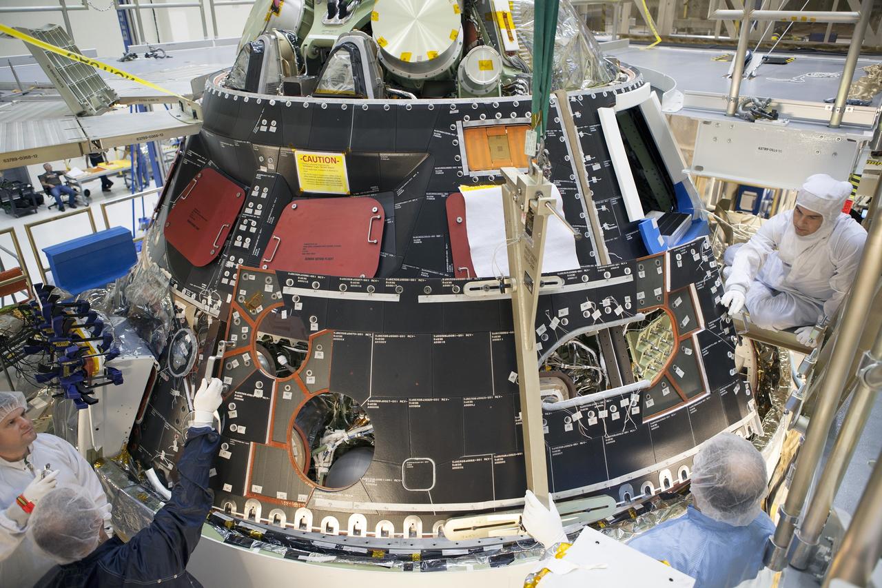 CAPE CANAVERAL, Fla. – Inside the Operations and Checkout Building high bay at NASA's Kennedy Space Center in Florida, technicians dressed in clean-room suits install a back shell tile panel onto the Orion crew module. Preparations are underway for Exploration Flight Test-1, or EFT-1. Orion is the exploration spacecraft designed to carry astronauts to destinations not yet explored by humans, including an asteroid and Mars. It will have emergency abort capability, sustain the crew during space travel and provide safe re-entry from deep space return velocities. The first unpiloted test flight of the Orion is scheduled to launch later this year atop a Delta IV rocket from Cape Canaveral Air Force Station in Florida to an altitude of 3,600 miles above the Earth's surface. The two-orbit, four-hour flight test will help engineers evaluate the systems critical to crew safety including the heat shield, parachute system and launch abort system. For more information, visit http://www.nasa.gov/orion. Photo credit: NASA/Dimitri Gerondidakis