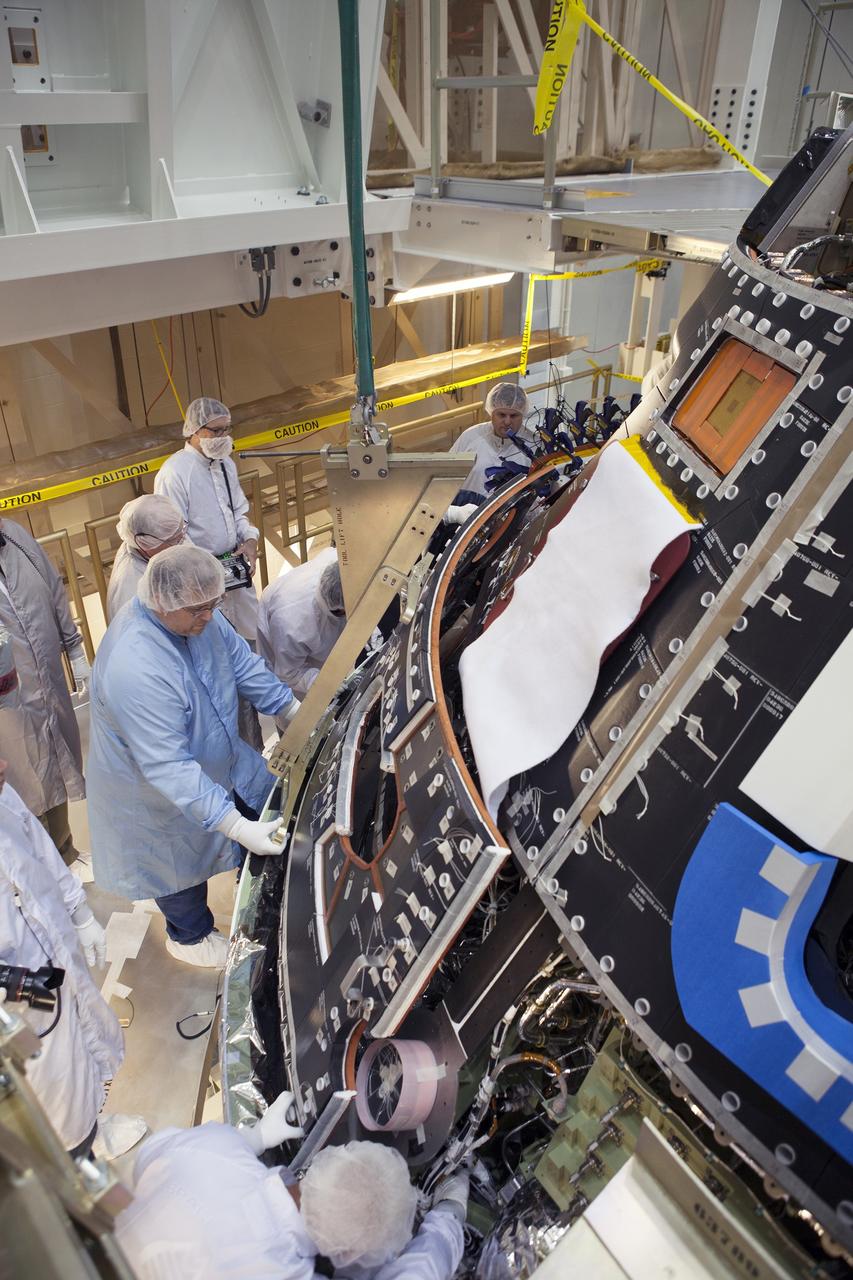CAPE CANAVERAL, Fla. – Inside the Operations and Checkout Building high bay at NASA's Kennedy Space Center in Florida, technicians dressed in clean-room suits install a back shell tile panel onto the Orion crew module. Preparations are underway for Exploration Flight Test-1, or EFT-1. Orion is the exploration spacecraft designed to carry astronauts to destinations not yet explored by humans, including an asteroid and Mars. It will have emergency abort capability, sustain the crew during space travel and provide safe re-entry from deep space return velocities. The first unpiloted test flight of the Orion is scheduled to launch later this year atop a Delta IV rocket from Cape Canaveral Air Force Station in Florida to an altitude of 3,600 miles above the Earth's surface. The two-orbit, four-hour flight test will help engineers evaluate the systems critical to crew safety including the heat shield, parachute system and launch abort system. For more information, visit http://www.nasa.gov/orion. Photo credit: NASA/Dimitri Gerondidakis