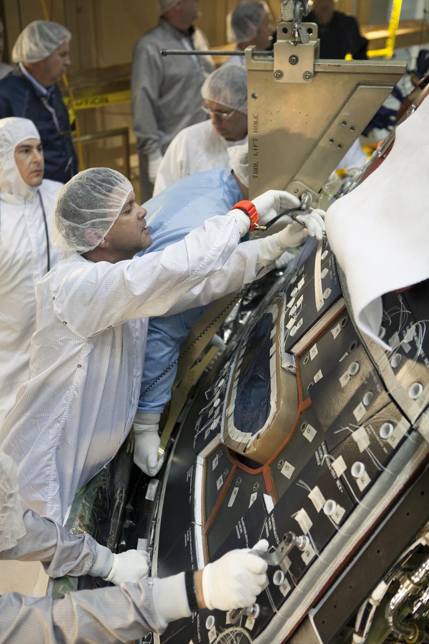 CAPE CANAVERAL, Fla. – Inside the Operations and Checkout Building high bay at NASA's Kennedy Space Center in Florida, technicians dressed in clean-room suits install a back shell tile panel onto the Orion crew module. Preparations are underway for Exploration Flight Test-1, or EFT-1. Orion is the exploration spacecraft designed to carry astronauts to destinations not yet explored by humans, including an asteroid and Mars. It will have emergency abort capability, sustain the crew during space travel and provide safe re-entry from deep space return velocities. The first unpiloted test flight of the Orion is scheduled to launch later this year atop a Delta IV rocket from Cape Canaveral Air Force Station in Florida to an altitude of 3,600 miles above the Earth's surface. The two-orbit, four-hour flight test will help engineers evaluate the systems critical to crew safety including the heat shield, parachute system and launch abort system. For more information, visit http://www.nasa.gov/orion. Photo credit: NASA/Dimitri Gerondidakis