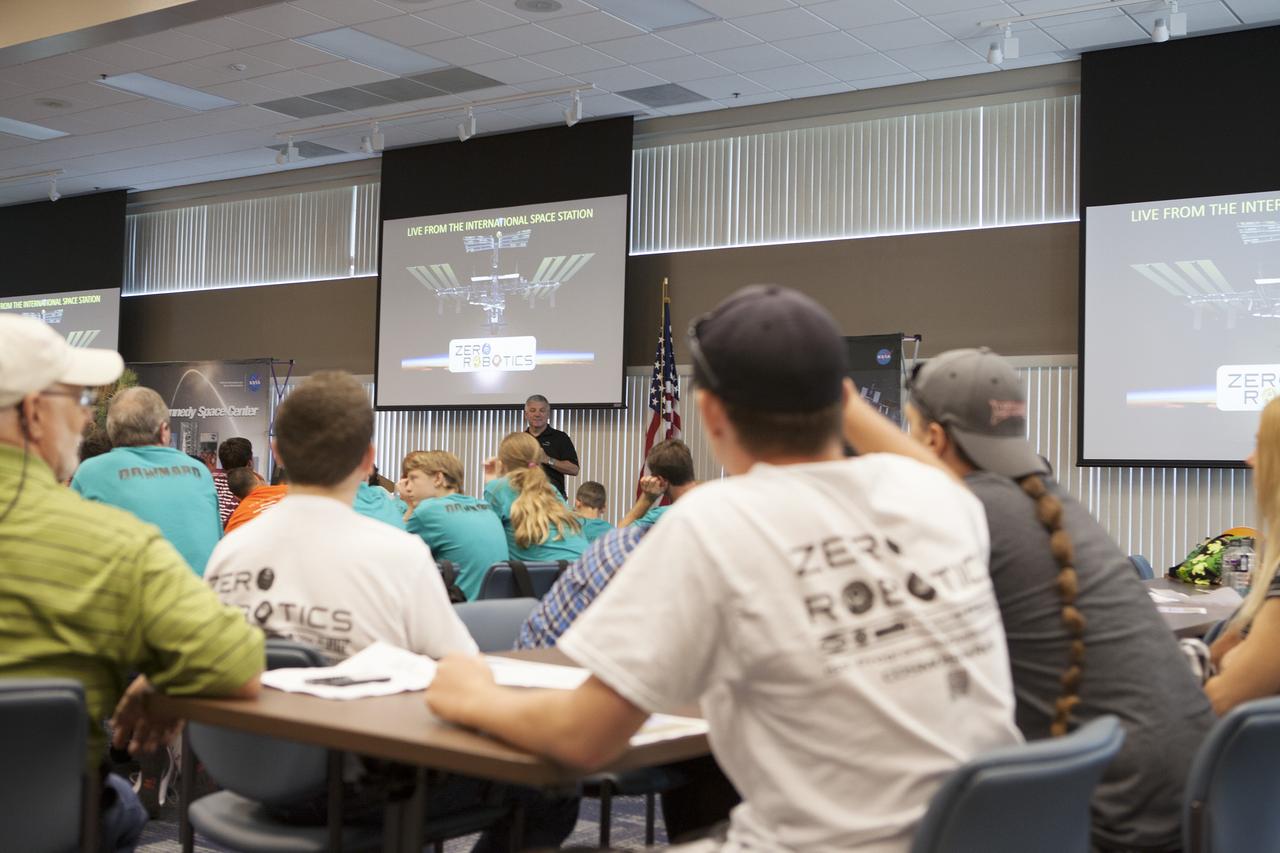 CAPE CANAVERAL, Fla. – Former astronaut Greg Johnson, executive director of the Center for the Advancement of Science in Space, talks to Florida middle school students and their teachers before the start of the Zero Robotics finals competition at NASA Kennedy Space Center's Space Station Processing Facility in Florida. Students designed software to control Synchronized Position Hold Engage and Reorient Experimental Satellites, or SPHERES, and competed with other teams locally. The Zero Robotics is a robotics programming competition where the robots are SPHERES. The competition starts online, where teams program the SPHERES to solve an annual challenge. After several phases of virtual competition in a simulation environment that mimics the real SPHERES, finalists are selected to compete in a live championship aboard the space station. Students compete to win a technically challenging game by programming their strategies into the SPHERES satellites. The programs are autonomous and the students cannot control the satellites during the test. Photo credit: NASA/Daniel Casper