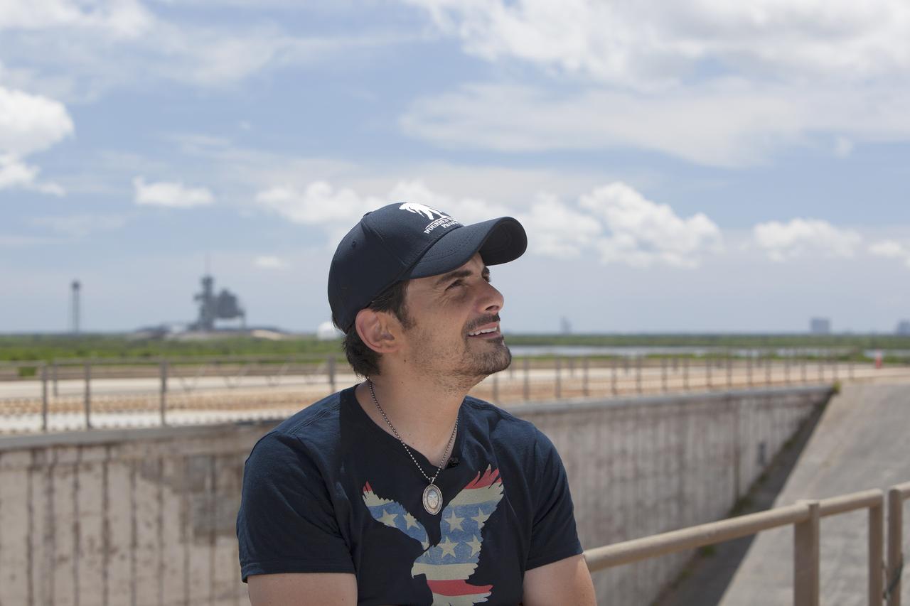 CAPE CANAVERAL, Fla. – Singer-songwriter Brad Paisley announces the release of a new song titled "American Flag on the Moon" from Launch Pad 39B at NASA’s Kennedy Space Center in Florida. In the background is Launch Pad 39A from which the Apollo moon landing missions were launched. Upon seeing Paisley's Twitter post that he was at NASA's Apollo launch pad leaking his new song, astronaut Reid Wiseman responded, "Hold on @BradPaisley, we don't usually like leaks at the launch pad." Wiseman is a member of the Expedition 40 crew currently in Earth orbit on the International Space Station. For more on Kennedy Space Center, visit http://www.nasa.gov/kennedy. To read more of Wiseman's Twitter posts from the station, go to https://twitter.com/astro_reid. Photo credit: NASA/Daniel Casper