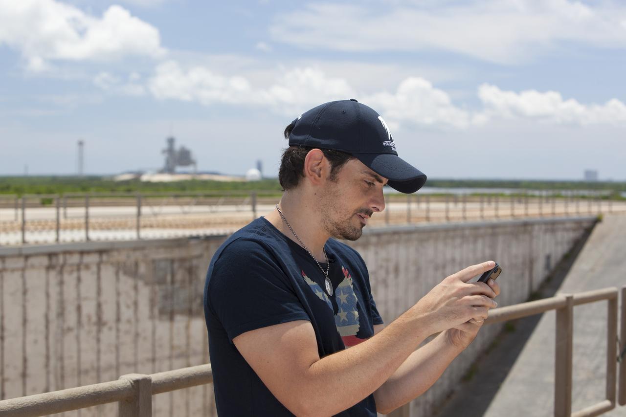 CAPE CANAVERAL, Fla. – At Launch Pad 39B at NASA’s Kennedy Space Center in Florida, singer-songwriter Brad Paisley receives a response from astronaut Reid Wiseman, an Expedition 40 crew member in Earth orbit on the International Space Station, after Paisley announced through social media the release of a new song titled "American Flag on the Moon." Wiseman responded, "Hold on @BradPaisley, we don't usually like leaks at the launch pad." In the background is Launch Pad 39A from which the Apollo moon landing missions were launched. For more on Kennedy Space Center, visit http://www.nasa.gov/kennedy. To read more of Wiseman's Twitter posts from the station, go to https://twitter.com/astro_reid. Photo credit: NASA/Daniel Casper