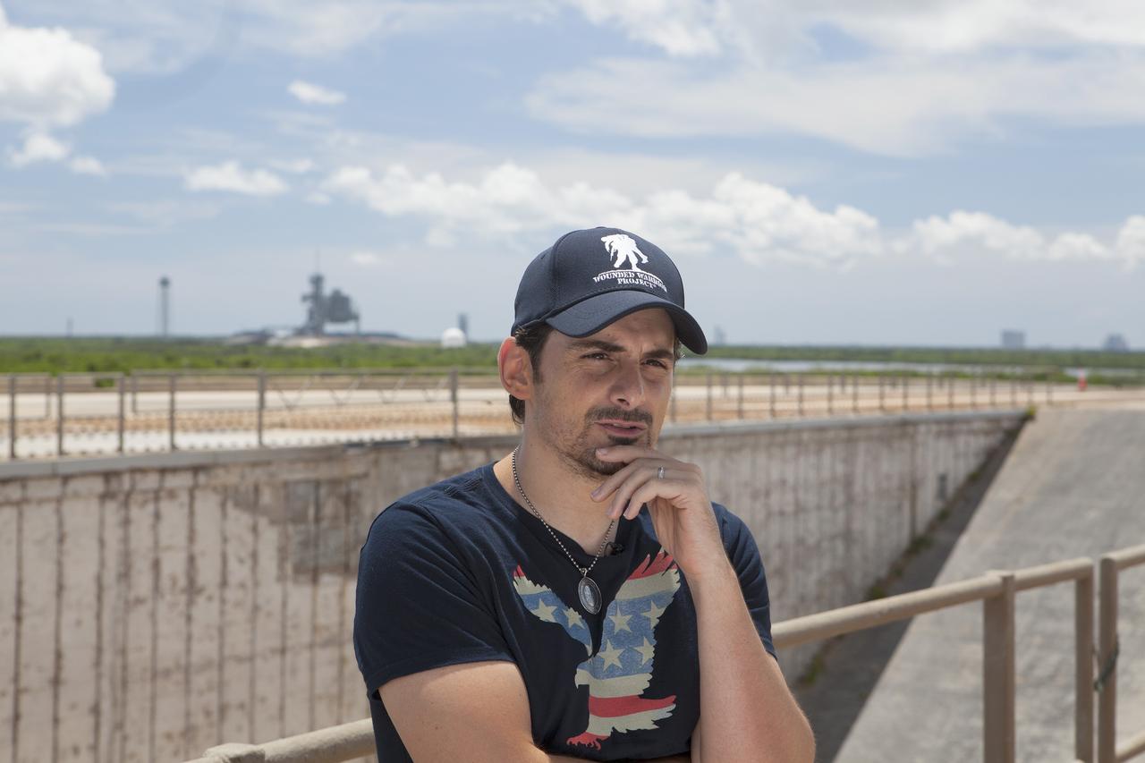 CAPE CANAVERAL, Fla. - During a visit to Launch Pad 39B at NASA’s Kennedy Space Center in Florida, singer-songwriter Brad Paisley records a public service announcement for the agency. Paisley also announced the release of a new song titled "American Flag on the Moon" with Launch Pad 39A from which the Apollo moon landing missions were launched in the background. The announcement drew an immediate response for astronaut Reid Wiseman, an Expedition 40 crew member in Earth orbit on the International Space Station.    For more on Kennedy Space Center, visit http://www.nasa.gov/kennedy. To read more of Wiseman's Twitter posts from the station, go to https://twitter.com/astro_reid. Photo credit: NASA/Daniel Casper