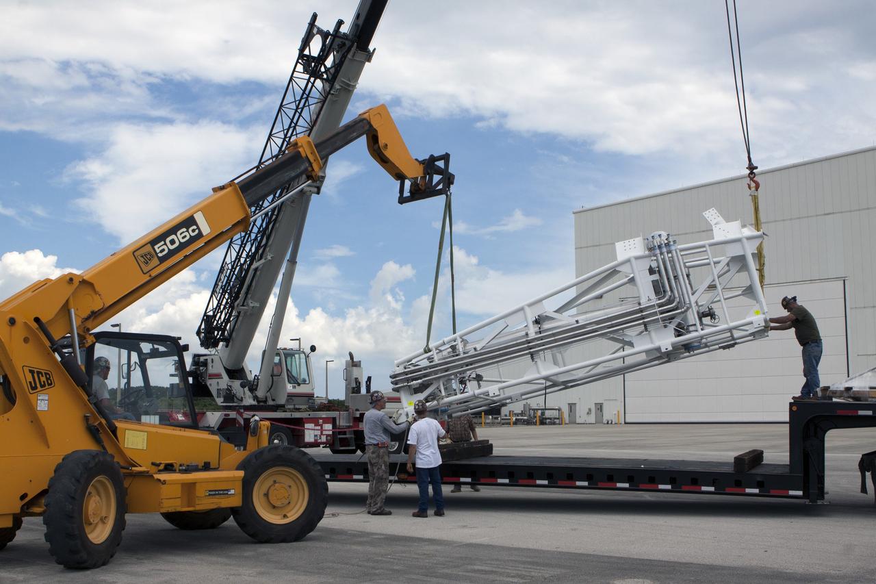 CAPE CANAVERAL, Fla. – Part of the umbilical swing arm for Exploration Flight Test 1, or EFT-1, arrives at the Horizontal Integration Facility near Space Launch Complex 37 at Cape Canaveral Air Force Station in Florida and is being lifted by crane from its transporter. The swing arm is the uppermost of three swing arms that will be attached to the fixed umbilical tower on the launch pad.    The swing arm will carry umbilicals that will be mated to Orion's launch abort system and environmental control system. During launch, the umbilicals will pull away from Orion and the United Launch Alliance Delta IV Heavy rocket at T-0. During the EFT-1 mission, Orion will travel farther into space than any human spacecraft has gone in more than 40 years.  The data gathered during the flight will influence design decisions, validate existing computer models and innovative new approaches to space systems development, as well as reduce overall mission risks and costs for later Orion flights. Liftoff of Orion on its first flight test is planned for fall 2014. Photo credit: NASA/Kim Shiflett