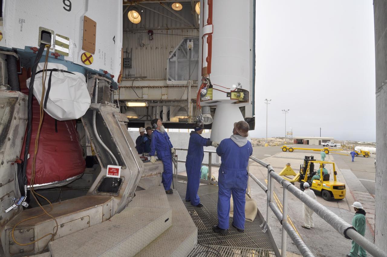 VANDENBERG AIR FORCE BASE, Calif. – Workers monitor a second solid rocket motor for the Delta II rocket for NASA's Soil Moisture Active Passive mission, or SMAP, as it is lowered into position beside the rocket's first stage in the mobile service tower at Space Launch Complex 2 on Vandenberg Air Force Base in California.    SMAP will be launched on a Delta II 7320 configuration vehicle featuring a United Launch Alliance first stage booster powered by an Aerojet Rocketdyne RS-27A main engine and three Alliant Techsystems, or ATK, strap-on solid rocket motors. Once on station in Earth orbit, SMAP will provide global measurements of soil moisture and its freeze/thaw state. These measurements will be used to enhance understanding of processes that link the water, energy and carbon cycles, and to extend the capabilities of weather and climate prediction models. SMAP data also will be used to quantify net carbon flux in boreal landscapes and to develop improved flood prediction and drought monitoring capabilities. Launch is scheduled for no earlier than November 2014. To learn more about SMAP, visit http://smap.jpl.nasa.gov.  Photo credit: NASA/Randy Beaudoin