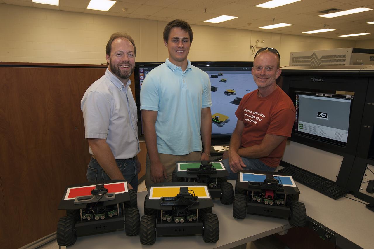 CAPE CANAVERAL, Fla. – NASA's Kurt Leucht, from left, is working with undergraduate intern Gil Montague and post-graduate intern Karl Stolleis to develop the software that will control independent robots in a way that mimics the process ants use to scout for and then collect resources. Photo credit: NASA/Dmitri Gerondidakis