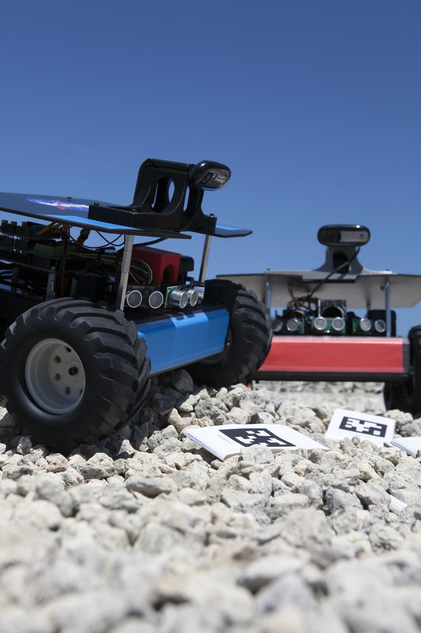 CAPE CANAVERAL, Fla. --  Two of the four "Swarmies" robots stand in front of the bar code markers they will track as they roll over rough ground near the Launch Control Center at NASA's Kennedy Space Center in Florida. Photo credit: NASA/Daniel Casper