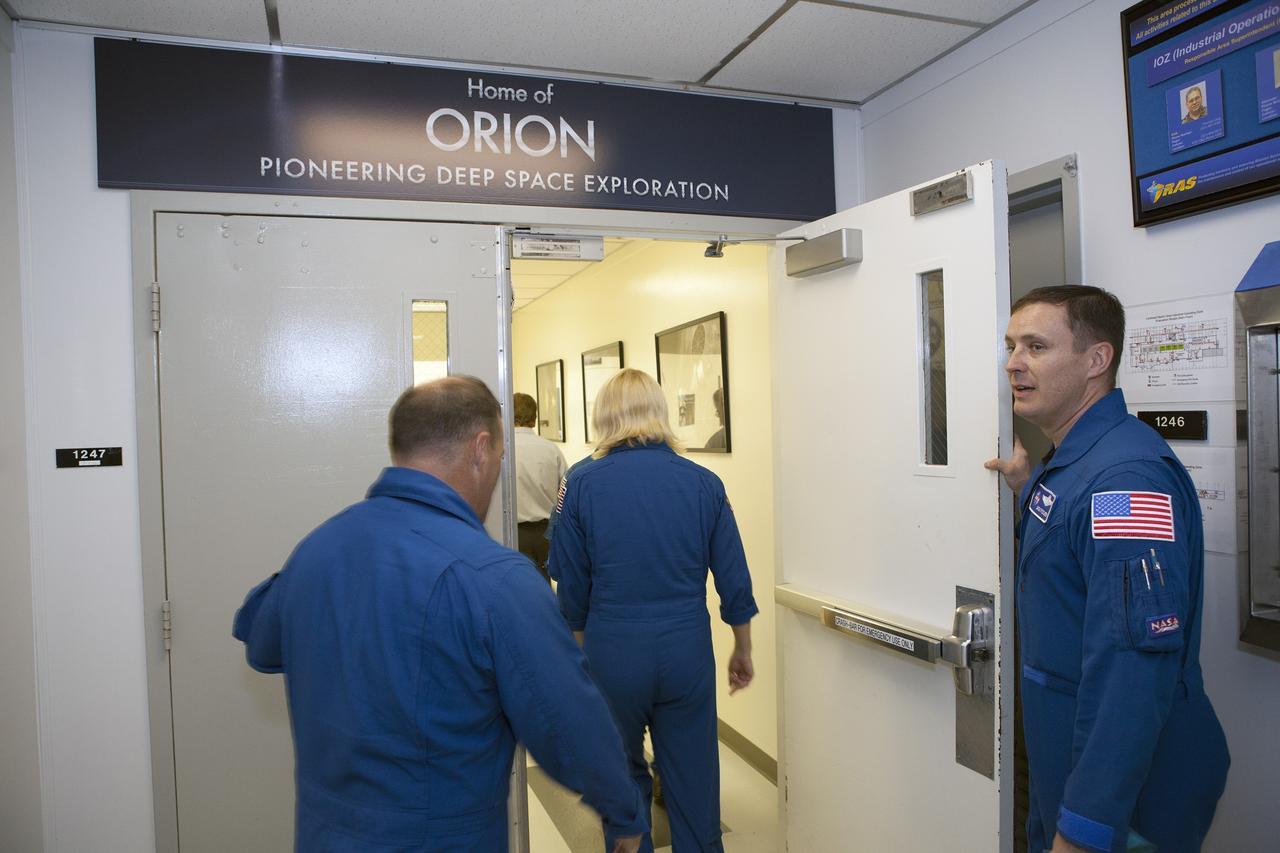 CAPE CANAVERAL, Fla. – NASA astronauts tour the Neil Armstrong Operations and Checkout Building high bay at NASA's Kennedy Space Center in Florida, and view the Orion forward bay cover for Exploration Flight Test-1. Holding the door is Jack Fischer. Going through the entrance are Katie Rubins and Scott Tingle. Orion is the exploration spacecraft designed to carry astronauts to destinations not yet explored by humans, including an asteroid and Mars. It will have emergency abort capability, sustain the crew during space travel and provide safe re-entry from deep space return velocities. The first unpiloted test flight of Orion is scheduled to launch in 2014 atop a United Launch Alliance Delta IV rocket and in 2018 on NASA’s Space Launch System rocket. For more information, visit www.nasa.gov/orion. Photo credit: Dimitri Gerondidakis