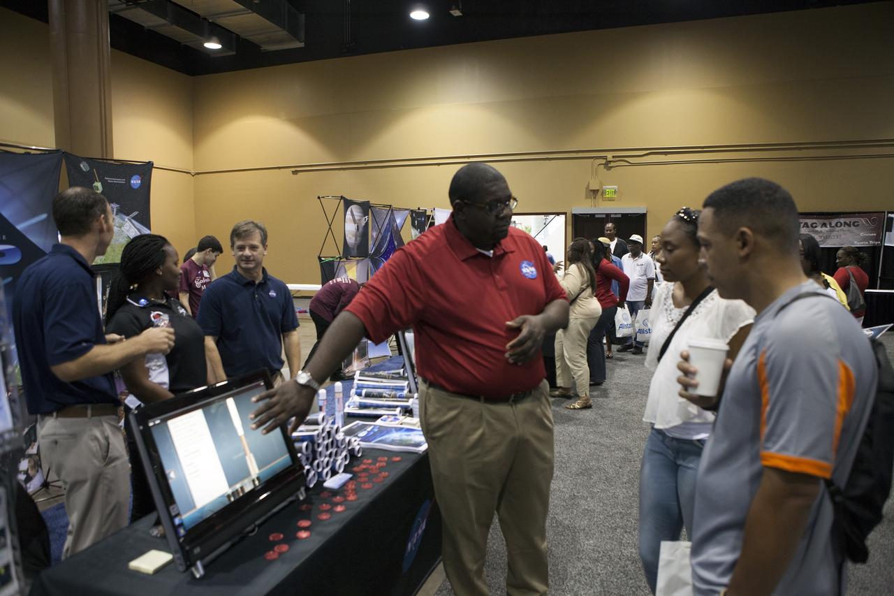 KISSIMMEE, Fla. – Guests at the Tom Joyner Family Reunion listen as Malcom Boston of the Fleet System Integration Branch of the Launch Services Program LSP explains a computer demonstration on rockets. Behind the table, from the left, are Brian Norton, Emily Fields and Randy Mizelle, all from the Program Planning Office in LSP.      The Tom Joyner Family Reunion is designed to present uplifting programs, entertainment and information about growing, diverse communities. An annual event of the nationally-syndicated Tom Joyner Morning Show, the many exhibits included NASA's participation focusing on encouraging young people to consider studies and careers in STEM -- science, technology, engineering and math. NASA's Education Division promoted the benefits of math and scientific learning along with career opportunities offered by the space agency. The activities took place at the Gaylord Palms Resort in Kissimmee, Florida, during the Labor Day weekend. Photo credit: NASA/Daniel Casper
