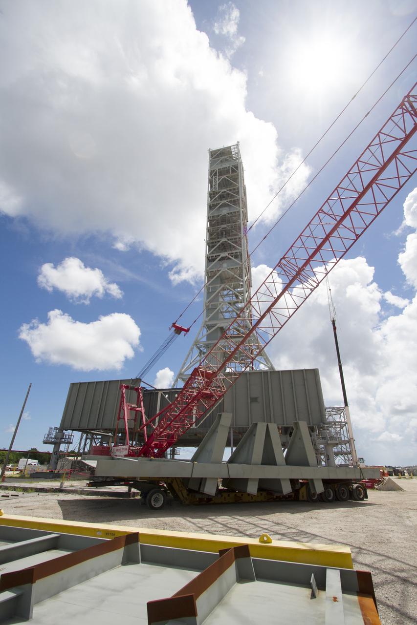 CAPE CANAVERAL, Fla. – Modifications continue on the Mobile Launcher, or ML, at the Mobile Launcher Park Site at NASA’s Kennedy Space Center in Florida. A crane is in place to lift a new steel beam for installation on the ML structure. The ML is being modified and strengthened to accommodate the weight, size and thrust at launch of NASA's Space Launch System, or SLS, and Orion spacecraft.    In 2013, the agency awarded a contract to J.P. Donovan Construction Inc. of Rockledge, Fla., to modify the ML, which is one of the key elements of ground support equipment that is being upgraded by the Ground Systems Development and Operations Program at Kennedy. The existing 24-foot exhaust hole is being enlarged and strengthened for the larger, heavier SLS rocket. The ML will carry the SLS rocket and Orion spacecraft to Launch Pad 39B for its first uncrewed mission, Exploration Mission-1, in 2018. Photo credit: NASA/Cory Huston