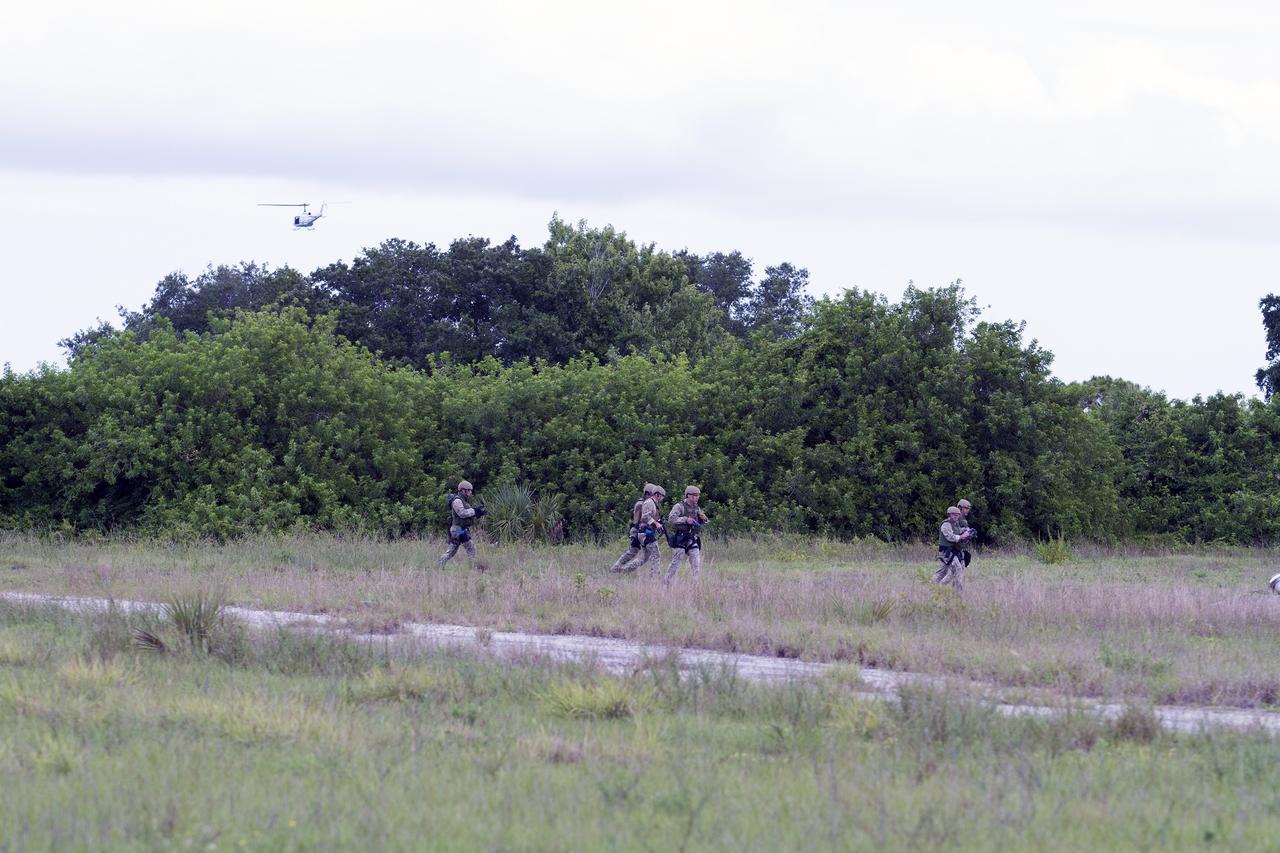 CAPE CANAVERAL, Fla. – Emergency Response Team officers from the Protective Services branch of NASA's Kennedy Space Center in Florida move through a field on their way to an objective during a training exercise simulating a situation the team could confront at the center. A Huey helicopter from the Air Operations branch at Kennedy is visible in the background flying out of the training area after delivering the officers. Photo credit: NASA/Dan Casper