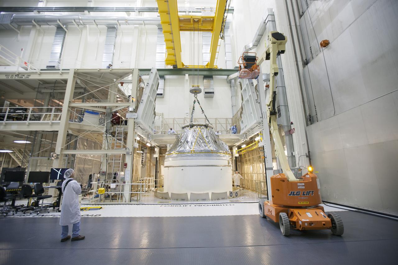 CAPE CANAVERAL, Fla. – Inside the Neil Armstrong Operations and Checkout Building high bay at NASA's Kennedy Space Center in Florida, a crane slowly lifts the Orion crew and service module stack for Exploration Flight Test-1 out of the test cell. Orion will be transferred to a mating device.    Orion is the exploration spacecraft designed to carry astronauts to destinations not yet explored by humans, including an asteroid and Mars. It will have emergency abort capability, sustain the crew during space travel and provide safe re-entry from deep space return velocities. The first unpiloted test flight of the Orion is scheduled to launch later this year atop a Delta IV Heavy rocket from Cape Canaveral Air Force Station in Florida to an altitude of 3,600 miles above the Earth's surface. The two-orbit, four-hour flight test will help engineers evaluate the systems critical to crew safety including the heat shield, parachute system and launch abort system. For more information, visit http://www.nasa.gov/orion. Photo credit: NASA/Ben Smegelsky