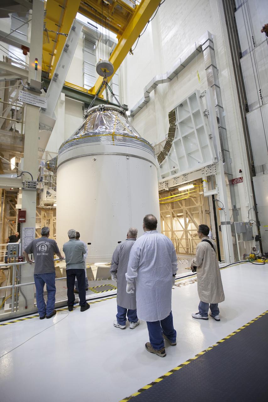 CAPE CANAVERAL, Fla. – Inside the Neil Armstrong Operations and Checkout Building high bay at NASA's Kennedy Space Center in Florida, technicians monitor the progress as a crane slowly lifts the Orion crew and service module stack for Exploration Flight Test-1 out of the test cell. Orion will be transferred to a mating device.    Orion is the exploration spacecraft designed to carry astronauts to destinations not yet explored by humans, including an asteroid and Mars. It will have emergency abort capability, sustain the crew during space travel and provide safe re-entry from deep space return velocities. The first unpiloted test flight of the Orion is scheduled to launch later this year atop a Delta IV Heavy rocket from Cape Canaveral Air Force Station in Florida to an altitude of 3,600 miles above the Earth's surface. The two-orbit, four-hour flight test will help engineers evaluate the systems critical to crew safety including the heat shield, parachute system and launch abort system. For more information, visit http://www.nasa.gov/orion. Photo credit: NASA/Ben Smegelsky