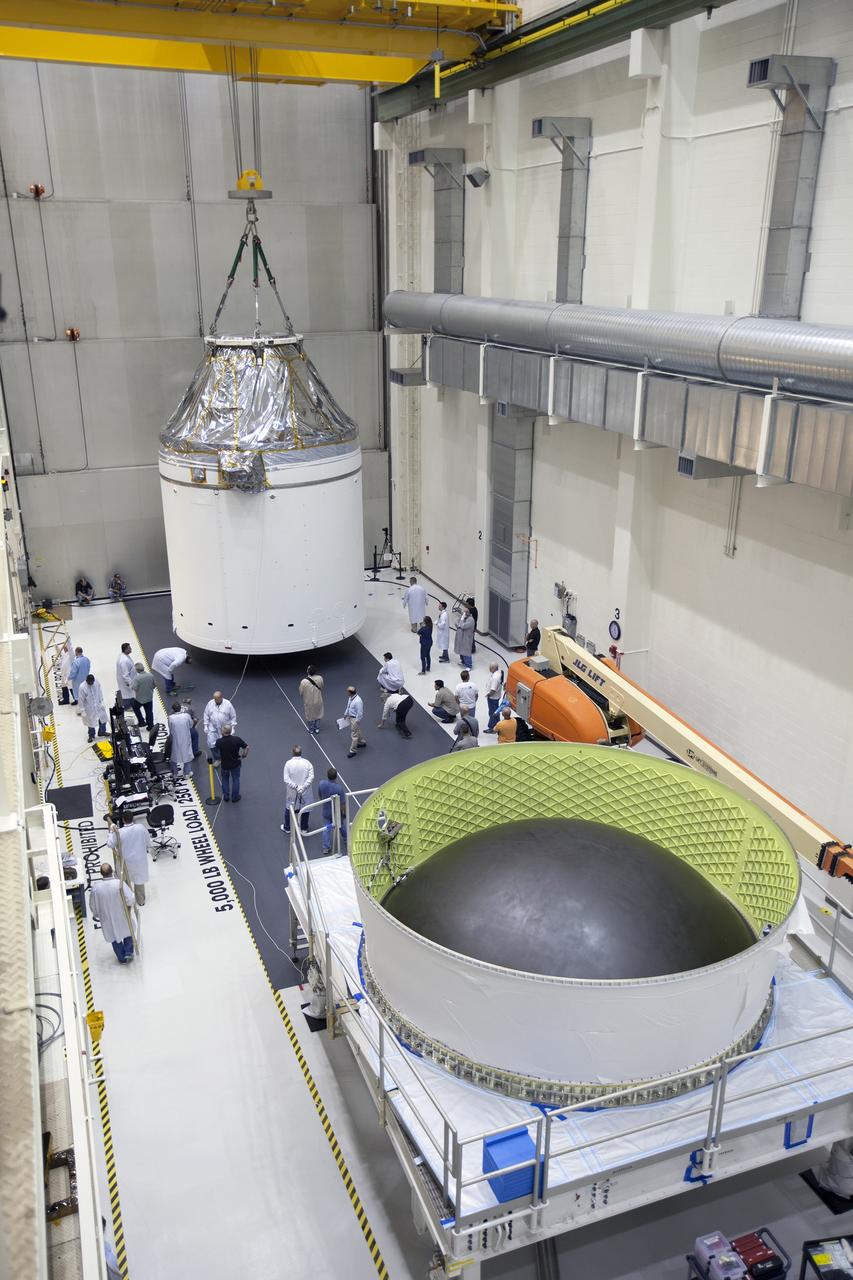 CAPE CANAVERAL, Fla. – Inside the Neil Armstrong Operations and Checkout Building high bay at NASA's Kennedy Space Center in Florida, the Orion crew and service module stack for Exploration Flight Test-1 was lifted by crane out of the test cell and is being moved along the center aisle. Orion will be transferred to a mating device. A protective covering surrounds the crew module.    Orion is the exploration spacecraft designed to carry astronauts to destinations not yet explored by humans, including an asteroid and Mars. It will have emergency abort capability, sustain the crew during space travel and provide safe re-entry from deep space return velocities. The first unpiloted test flight of the Orion is scheduled to launch later this year atop a Delta IV Heavy rocket from Cape Canaveral Air Force Station in Florida to an altitude of 3,600 miles above the Earth's surface. The two-orbit, four-hour flight test will help engineers evaluate the systems critical to crew safety including the heat shield, parachute system and launch abort system. For more information, visit http://www.nasa.gov/orion. Photo credit: NASA/Ben Smegelsky