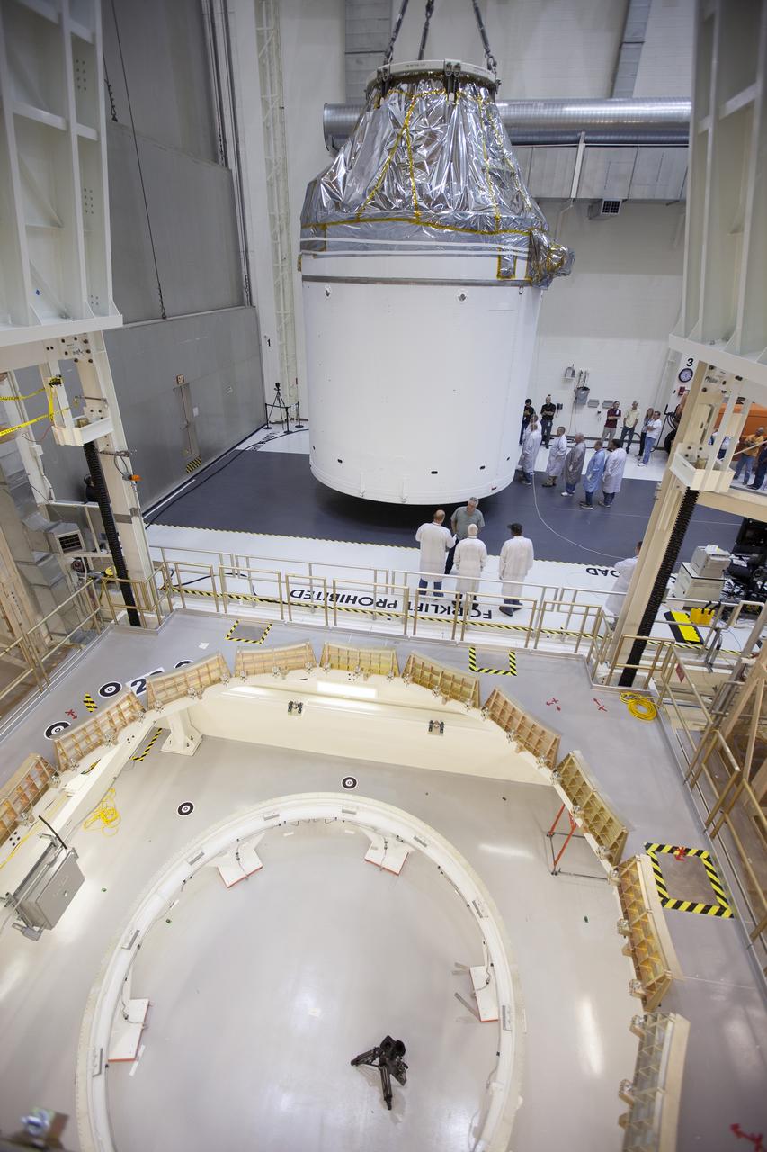 CAPE CANAVERAL, Fla. – Inside the Neil Armstrong Operations and Checkout Building high bay at NASA's Kennedy Space Center in Florida, the Orion crew and service module stack for Exploration Flight Test-1 was lifted by crane out of the test cell and is being moved along the center aisle. Orion will be transferred to a mating device. A protective covering surrounds the crew module.    Orion is the exploration spacecraft designed to carry astronauts to destinations not yet explored by humans, including an asteroid and Mars. It will have emergency abort capability, sustain the crew during space travel and provide safe re-entry from deep space return velocities. The first unpiloted test flight of the Orion is scheduled to launch later this year atop a Delta IV Heavy rocket from Cape Canaveral Air Force Station in Florida to an altitude of 3,600 miles above the Earth's surface. The two-orbit, four-hour flight test will help engineers evaluate the systems critical to crew safety including the heat shield, parachute system and launch abort system. For more information, visit http://www.nasa.gov/orion. Photo credit: NASA/Ben Smegelsky