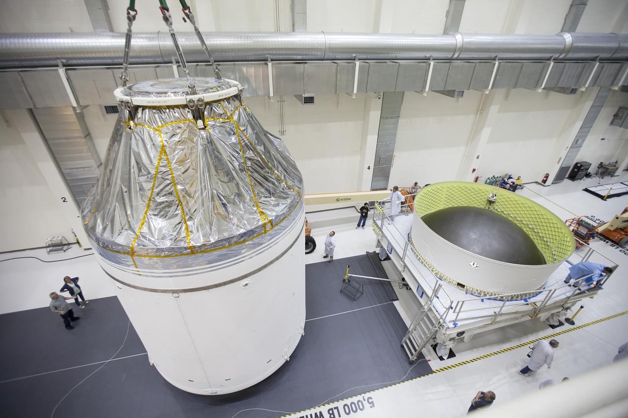 CAPE CANAVERAL, Fla. – Inside the Neil Armstrong Operations and Checkout Building high bay at NASA's Kennedy Space Center in Florida, the Orion crew and service module stack for Exploration Flight Test-1 was lifted by crane out of the test cell and is being moved along the center aisle toward the mating device.  A protective covering surrounds the crew module.    Orion is the exploration spacecraft designed to carry astronauts to destinations not yet explored by humans, including an asteroid and Mars. It will have emergency abort capability, sustain the crew during space travel and provide safe re-entry from deep space return velocities. The first unpiloted test flight of the Orion is scheduled to launch later this year atop a Delta IV Heavy rocket from Cape Canaveral Air Force Station in Florida to an altitude of 3,600 miles above the Earth's surface. The two-orbit, four-hour flight test will help engineers evaluate the systems critical to crew safety including the heat shield, parachute system and launch abort system. For more information, visit http://www.nasa.gov/orion. Photo credit: NASA/Ben Smegelsky