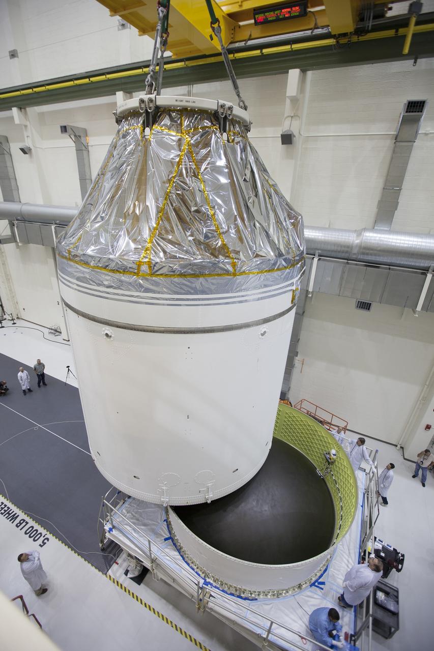 CAPE CANAVERAL, Fla. – Inside the Neil Armstrong Operations and Checkout Building high bay at NASA's Kennedy Space Center in Florida, the Orion crew and service module stack for Exploration Flight Test-1 was lifted by crane out of the test cell and is being lowered onto a mating device. A protective covering surrounds the crew module.     Orion is the exploration spacecraft designed to carry astronauts to destinations not yet explored by humans, including an asteroid and Mars. It will have emergency abort capability, sustain the crew during space travel and provide safe re-entry from deep space return velocities. The first unpiloted test flight of the Orion is scheduled to launch later this year atop a Delta IV Heavy rocket from Cape Canaveral Air Force Station in Florida to an altitude of 3,600 miles above the Earth's surface. The two-orbit, four-hour flight test will help engineers evaluate the systems critical to crew safety including the heat shield, parachute system and launch abort system. For more information, visit http://www.nasa.gov/orion. Photo credit: NASA/Ben Smegelsky