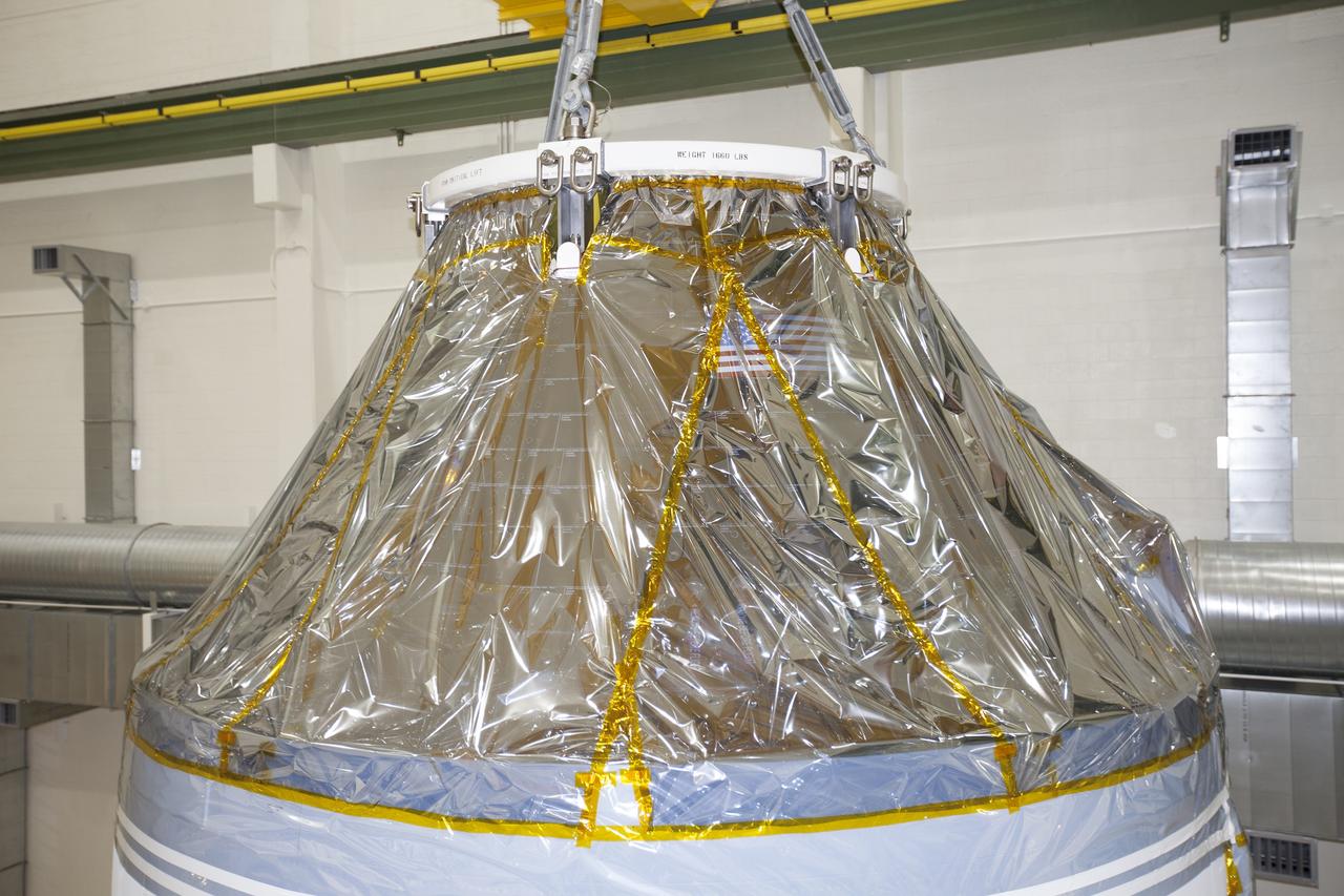 CAPE CANAVERAL, Fla. – Inside the Neil Armstrong Operations and Checkout Building high bay at NASA's Kennedy Space Center in Florida, the Orion crew and service module stack for Exploration Flight Test-1 was lifted by crane out of the test cell and is being lowered onto a mating device A protective covering surrounds the crew module.      Orion is the exploration spacecraft designed to carry astronauts to destinations not yet explored by humans, including an asteroid and Mars. It will have emergency abort capability, sustain the crew during space travel and provide safe re-entry from deep space return velocities. The first unpiloted test flight of the Orion is scheduled to launch later this year atop a Delta IV Heavy rocket from Cape Canaveral Air Force Station in Florida to an altitude of 3,600 miles above the Earth's surface. The two-orbit, four-hour flight test will help engineers evaluate the systems critical to crew safety including the heat shield, parachute system and launch abort system. For more information, visit http://www.nasa.gov/orion. Photo credit: NASA/Ben Smegelsky
