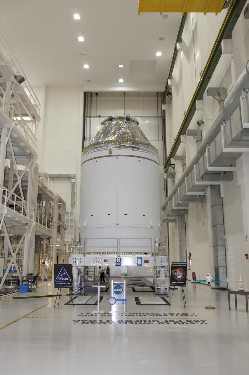 CAPE CANAVERAL, Fla. – The Orion crew module, stacked atop its service module, is positioned in the Neil Armstrong Operations and Checkout Building high bay at NASA's Kennedy Space Center in Florida. A ceremony will begin to officially turn over the Orion spacecraft for Exploration Flight Test-1 to Lockheed Martin Ground Operations from Orion Assembly, Integration and Production.    Orion is the exploration spacecraft designed to carry astronauts to destinations not yet explored by humans, including an asteroid and Mars. It will have emergency abort capability, sustain the crew during space travel and provide safe re-entry from deep space return velocities. The first unpiloted test flight of the Orion is scheduled to launch atop a United Launch Alliance Delta IV Heavy rocket from Cape Canaveral Air Force Station in Florida in December to an altitude of 3,600 miles above the Earth's surface. The two-orbit, four-hour flight test will help engineers evaluate the systems critical to crew safety including the heat shield, parachute system and launch abort system. For more information, visit http://www.nasa.gov/orion. Photo credit: NASA/Daniel Casper