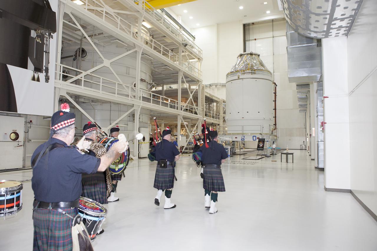 CAPE CANAVERAL, Fla. – Inside the Neil Armstrong Operations and Checkout Building high bay at NASA's Kennedy Space Center in Florida, members of the Brevard Police and Fire Pipes and Drums lead NASA and Lockheed Martin workers toward the Orion crew module, stacked atop its service module. A ceremony will begin to officially turn over the Orion spacecraft for Exploration Flight Test-1 to Lockheed Martin Ground Operations from Orion Assembly, Integration and Production.    Orion is the exploration spacecraft designed to carry astronauts to destinations not yet explored by humans, including an asteroid and Mars. It will have emergency abort capability, sustain the crew during space travel and provide safe re-entry from deep space return velocities. The first unpiloted test flight of the Orion is scheduled to launch atop a United Launch Alliance Delta IV Heavy rocket from Cape Canaveral Air Force Station in Florida in December to an altitude of 3,600 miles above the Earth's surface. The two-orbit, four-hour flight test will help engineers evaluate the systems critical to crew safety including the heat shield, parachute system and launch abort system. For more information, visit http://www.nasa.gov/orion. Photo credit: NASA/Daniel Casper
