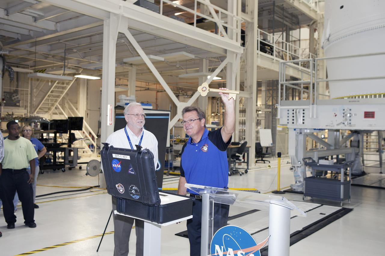 CAPE CANAVERAL, Fla. – During a ceremony inside the Neil Armstrong Operations and Checkout Building high bay at NASA's Kennedy Space Center in Florida, Jules Schneider, Lockheed Martin Orion Production Operations manager, holds the key to symbolically turn over the Orion spacecraft for Exploration Flight Test-1 to Ground Operations. Waiting to accept the key is Blake Hale, Lockheed Martin Ground Operations manager. Orion is the exploration spacecraft designed to carry astronauts to destinations not yet explored by humans, including an asteroid and Mars. It will have emergency abort capability, sustain the crew during space travel and provide safe re-entry from deep space return velocities. The first unpiloted test flight of the Orion is scheduled to launch atop a United Launch Alliance Delta IV Heavy rocket from Cape Canaveral Air Force Station in Florida in December to an altitude of 3,600 miles above the Earth's surface. The two-orbit, four-hour flight test will help engineers evaluate the systems critical to crew safety including the heat shield, parachute system and launch abort system. For more information, visit http://www.nasa.gov/orion. Photo credit: NASA/Daniel Casper