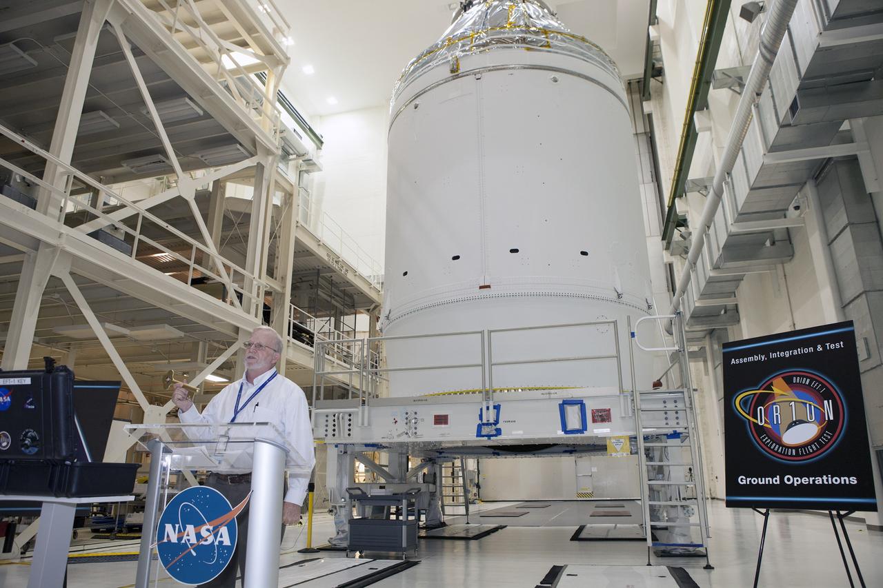 CAPE CANAVERAL, Fla. – Inside the Neil Armstrong Operations and Checkout Building high bay at NASA's Kennedy Space Center in Florida, Blake Hale, Lockheed Martin Ground Operations manager, speaks to NASA and Lockheed Martin workers during a ceremony to turn over Orion spacecraft for Exploration Flight Test-1 to Lockheed Martin Ground Operations from Orion Assembly, Integration and Production.      Orion is the exploration spacecraft designed to carry astronauts to destinations not yet explored by humans, including an asteroid and Mars. It will have emergency abort capability, sustain the crew during space travel and provide safe re-entry from deep space return velocities. The first unpiloted test flight of the Orion is scheduled to launch atop a United Launch Alliance Delta IV Heavy rocket from Cape Canaveral Air Force Station in Florida in December to an altitude of 3,600 miles above the Earth's surface. The two-orbit, four-hour flight test will help engineers evaluate the systems critical to crew safety including the heat shield, parachute system and launch abort system. For more information, visit http://www.nasa.gov/orion. Photo credit: NASA/Daniel Casper