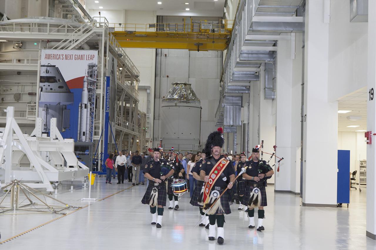 CAPE CANAVERAL, Fla. – Inside the Neil Armstrong Operations and Checkout Building high bay at NASA's Kennedy Space Center in Florida, members of the Brevard Police and Fire Pipes and Drums lead NASA and Lockheed Martin workers out of the high bay after a ceremony to turn over the Orion spacecraft for Exploration Flight Test-1 to Lockheed Martin Ground Operations from Orion Assembly, Integration and Production.       Orion is the exploration spacecraft designed to carry astronauts to destinations not yet explored by humans, including an asteroid and Mars. It will have emergency abort capability, sustain the crew during space travel and provide safe re-entry from deep space return velocities. The first unpiloted test flight of the Orion is scheduled to launch atop a United Launch Alliance Delta IV Heavy rocket from Cape Canaveral Air Force Station in Florida in December to an altitude of 3,600 miles above the Earth's surface. The two-orbit, four-hour flight test will help engineers evaluate the systems critical to crew safety including the heat shield, parachute system and launch abort system. For more information, visit http://www.nasa.gov/orion. Photo credit: NASA/Daniel Casper
