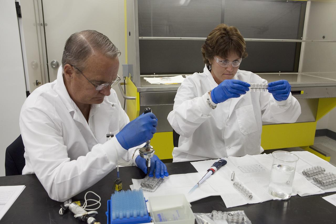 CAPE CANAVERAL, Fla. – Inside a laboratory in the Space Station Processing Facility at NASA's Kennedy Space Center in Florida, April Spinale, a payload integration specialist with Bionetics, and Ray Polniak, a quality assurance specialist with Dynamac, fill vials with clear water during an acceptance leak test on the hardware for the Protein Crystal Growth 2 experiment. They are both consultants for the Center for Advancement of Science in Space, or CASIS. The experiment is one of many that will be delivered to the International Space Station on the SpaceX-4 commercial cargo resupply mission. Kennedy's ISS Ground Processing and Research Project Office is providing the necessary laboratories, equipment, supplies and consumables for 61 principal investigators, including 17 from other countries, as they prepare their science experiments for flight. The SpaceX-4 flight is targeted to launch in September 2014. Photo credit: NASA/Dimitri Gerondidakis
