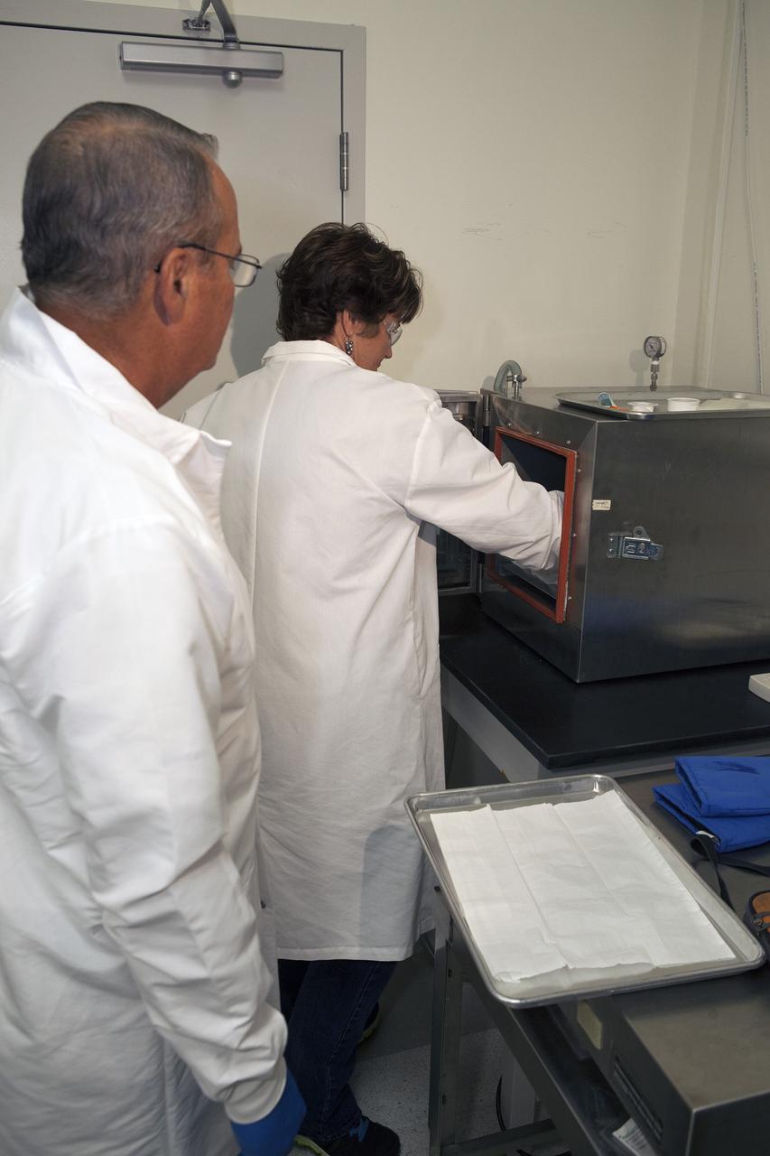 CAPE CANAVERAL, Fla. – Inside a laboratory in the Space Station Processing Facility at NASA's Kennedy Space Center in Florida, April Spinale, a payload integration specialist with Bionetics, and Ray Polniak, a quality assurance specialist with Dynamac, place a set of vials for the Protein Crystal Growth 2 experiment into a vacuum chamber for an acceptance leak test. The vials have been filled with clear water. The test will verify that the hardware is providing adequate containment for the liquids. Both are consultants for the Center for Advancement of Science in Space, or CASIS. The experiment is one of many that will be delivered to the International Space Station on the SpaceX-4 commercial cargo resupply mission. Kennedy's ISS Ground Processing and Research Project Office is providing the necessary laboratories, equipment, supplies and consumables for 61 principal investigators, including 17 from other countries, as they prepare their science experiments for flight. The SpaceX-4 flight is targeted to launch in September 2014. Photo credit: NASA/Dimitri Gerondidakis