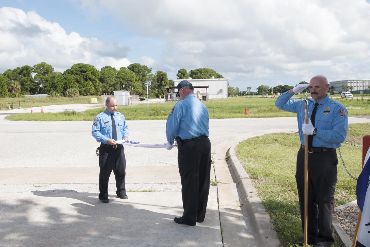 Cape Canaveral, Fla. – At Fire Station 1 at NASA’s Kennedy Space Center in Florida, Gabe Wingard and Steve Dudgeon, both with NASA's Protective Services, fold the commemorative flag during a ceremony held by Kennedy’s Fire and Rescue personnel. Kennedy Fire and Rescue Services commemorated the 13th anniversary of 9/11 with a ceremony that included a minute of silence at 10:28 a.m., which was the moment of collapse of the north tower of the World Trade Center. Photo credit: Jim Grossmann