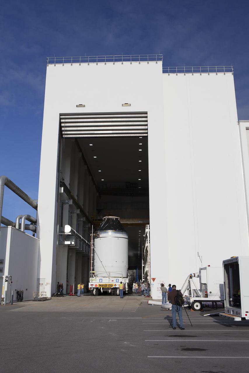 CAPE CANAVERAL, Fla. – The Orion crew module, stacked atop its service module, is moved slowly out of the Neil Armstrong Operations and Checkout Building high bay door at NASA's Kennedy Space Center in Florida. The spacecraft for Exploration Flight Test-1 will be transported to the Payload Hazardous Servicing Facility where it will be fueled ahead of its December flight test.    Orion is the exploration spacecraft designed to carry astronauts to destinations not yet explored by humans, including an asteroid and Mars. It will have emergency abort capability, sustain the crew during space travel and provide safe re-entry from deep space return velocities. The first unpiloted test flight of the Orion is scheduled to launch atop a United Launch Alliance Delta IV Heavy rocket from Cape Canaveral Air Force Station in Florida to an altitude of 3,600 miles above the Earth's surface. The two-orbit, four-hour flight test will help engineers evaluate the systems critical to crew safety including the heat shield, parachute system and launch abort system. For more information, visit http://www.nasa.gov/orion. Photo credit: NASA/Daniel Casper
