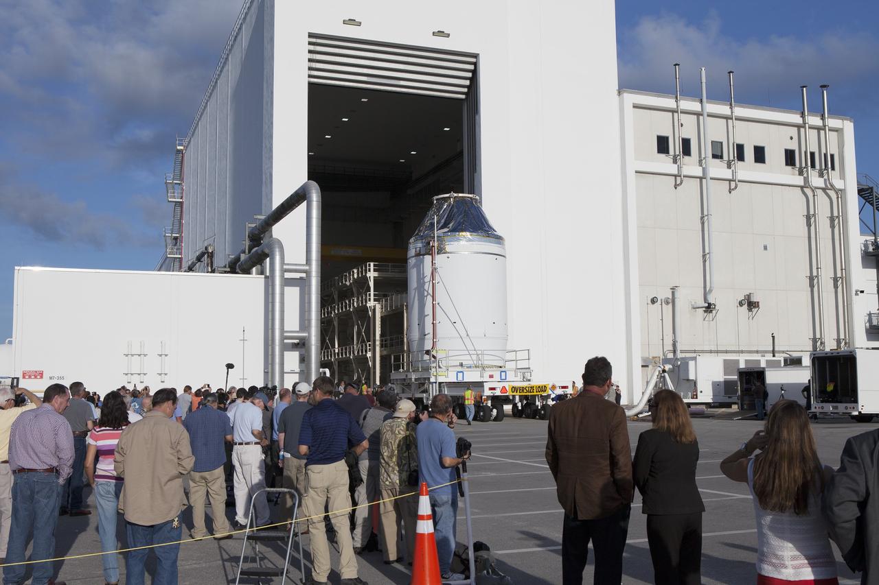 CAPE CANAVERAL, Fla. – Reporters and photographers watch as the Orion crew module, stacked atop its service module, moves out of the Neil Armstrong Operations and Checkout Building high bay at NASA's Kennedy Space Center in Florida. The spacecraft for Exploration Flight Test-1 will be transported to the Payload Hazardous Servicing Facility where it will be fueled ahead of its December flight test. Orion is the exploration spacecraft designed to carry astronauts to destinations not yet explored by humans, including an asteroid and Mars. It will have emergency abort capability, sustain the crew during space travel and provide safe re-entry from deep space return velocities. The first unpiloted test flight of the Orion is scheduled to launch atop a United Launch Alliance Delta IV Heavy rocket from Cape Canaveral Air Force Station in Florida to an altitude of 3,600 miles above the Earth's surface. The two-orbit, four-hour flight test will help engineers evaluate the systems critical to crew safety including the heat shield, parachute system and launch abort system. For more information, visit http://www.nasa.gov/orion. Photo credit: NASA/Daniel Casper