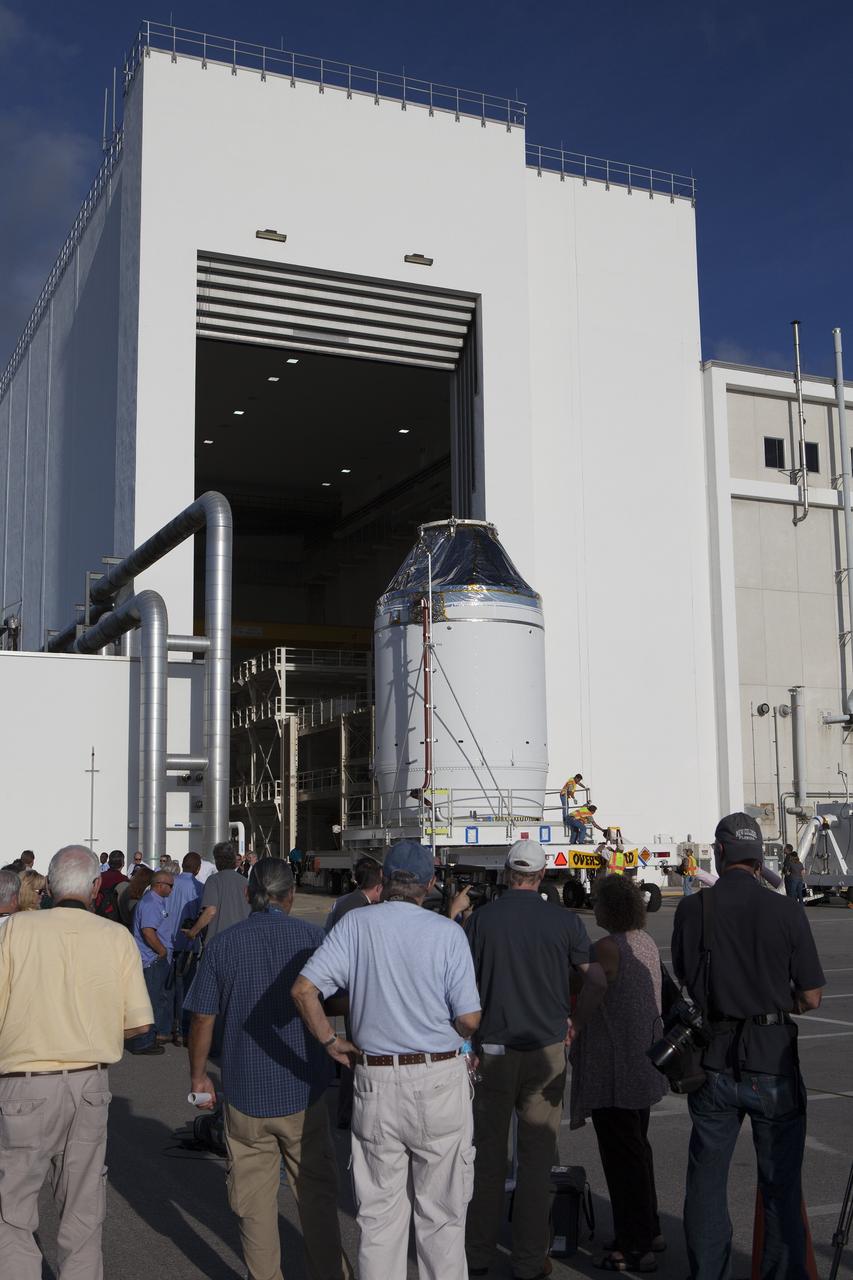 CAPE CANAVERAL, Fla. – Reporters and photographers watch as the Orion crew module, stacked atop its service module, moves out of the Neil Armstrong Operations and Checkout Building high bay at NASA's Kennedy Space Center in Florida. The spacecraft for Exploration Flight Test-1 will be transported to the Payload Hazardous Servicing Facility where it will be fueled ahead of its December flight test.    Orion is the exploration spacecraft designed to carry astronauts to destinations not yet explored by humans, including an asteroid and Mars. It will have emergency abort capability, sustain the crew during space travel and provide safe re-entry from deep space return velocities. The first unpiloted test flight of the Orion is scheduled to launch atop a United Launch Alliance Delta IV Heavy rocket from Cape Canaveral Air Force Station in Florida to an altitude of 3,600 miles above the Earth's surface. The two-orbit, four-hour flight test will help engineers evaluate the systems critical to crew safety including the heat shield, parachute system and launch abort system. For more information, visit http://www.nasa.gov/orion. Photo credit: NASA/Daniel Casper