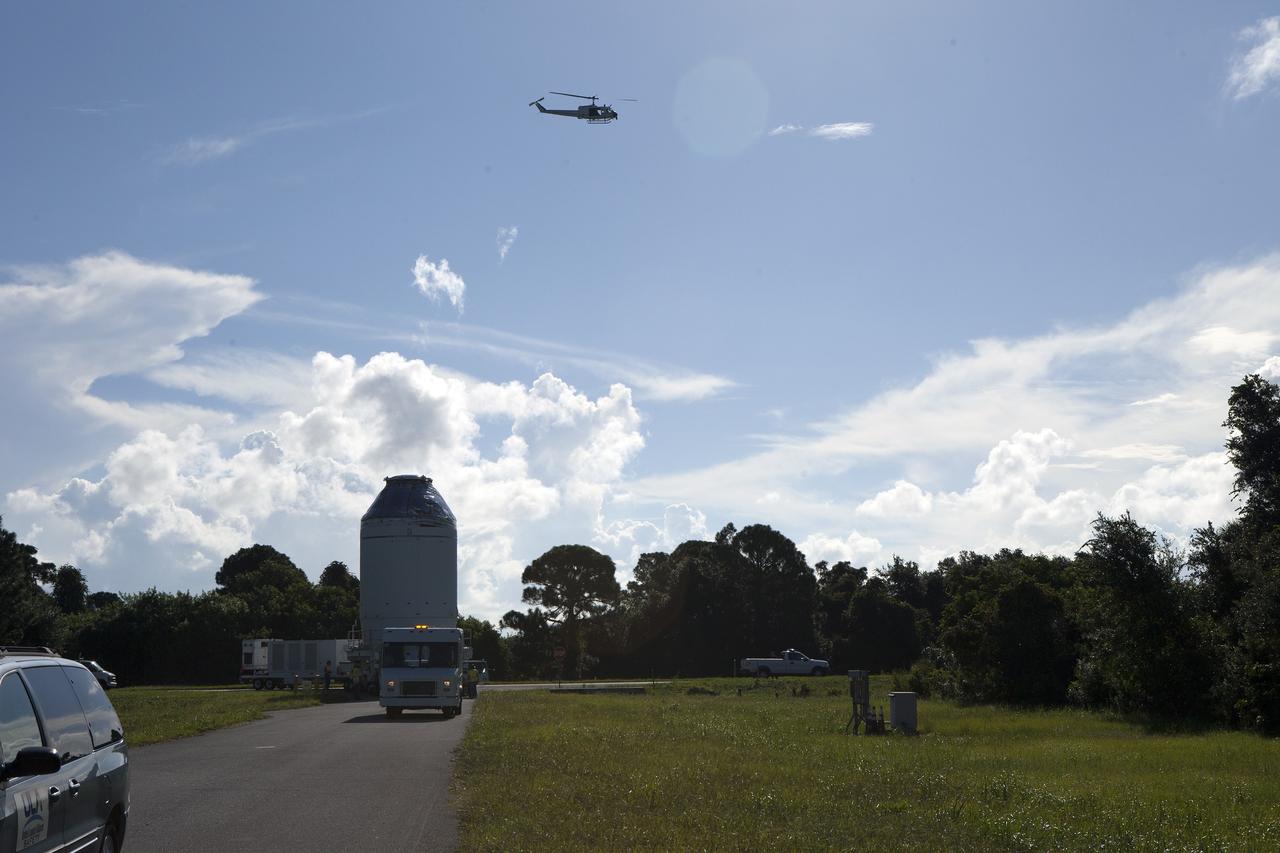 CAPE CANAVERAL, Fla. – A NASA helicopter flies overhead as the Orion crew module, stacked atop its service module, is transported to the Payload Hazardous Servicing Facility at NASA's Kennedy Space Center in Florida, where it will be fueled ahead of its December flight. The spacecraft for Exploration Flight Test-1 was moved out of the Neil Armstrong Operations and Checkout Building high bay. Orion is the exploration spacecraft designed to carry astronauts to destinations not yet explored by humans, including an asteroid and Mars. It will have emergency abort capability, sustain the crew during space travel and provide safe re-entry from deep space return velocities. The first unpiloted test flight of the Orion is scheduled to launch atop a United Launch Alliance Delta IV Heavy rocket from Cape Canaveral Air Force Station in Florida to an altitude of 3,600 miles above the Earth's surface. The two-orbit, four-hour flight test will help engineers evaluate the systems critical to crew safety including the heat shield, parachute system and launch abort system. For more information, visit http://www.nasa.gov/orion. Photo credit: NASA/Daniel Casper