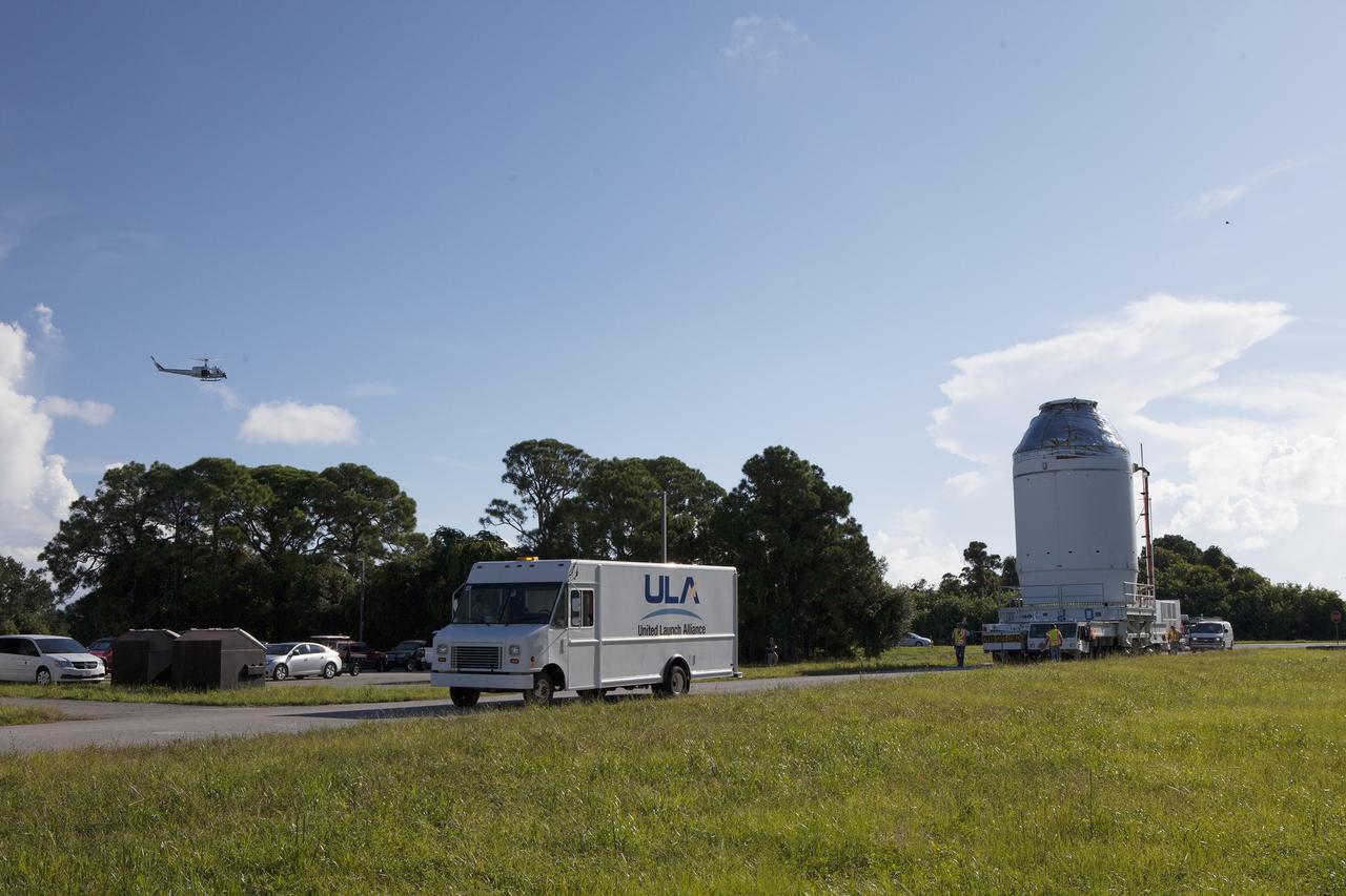 CAPE CANAVERAL, Fla. – A NASA helicopter flies overhead as the Orion crew module, stacked atop its service module, is transported to the Payload Hazardous Servicing Facility at NASA's Kennedy Space Center in Florida, where it will be fueled ahead of its December flight. The spacecraft for Exploration Flight Test-1 was moved out of the Neil Armstrong Operations and Checkout Building high bay.    Orion is the exploration spacecraft designed to carry astronauts to destinations not yet explored by humans, including an asteroid and Mars. It will have emergency abort capability, sustain the crew during space travel and provide safe re-entry from deep space return velocities. The first unpiloted test flight of the Orion is scheduled to launch atop a United Launch Alliance Delta IV Heavy rocket from Cape Canaveral Air Force Station in Florida to an altitude of 3,600 miles above the Earth's surface. The two-orbit, four-hour flight test will help engineers evaluate the systems critical to crew safety including the heat shield, parachute system and launch abort system. For more information, visit http://www.nasa.gov/orion. Photo credit: NASA/Daniel Casper