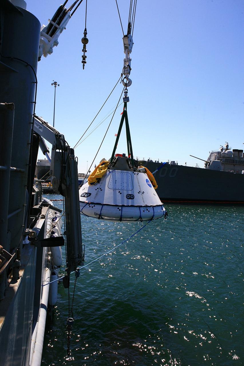 SAN DIEGO, Calif. – The Orion boilerplate test vehicle is slowly lowered by stationary crane toward the water during the first day of Underway Recovery Test 4A aboard the USS Salvor, a safeguard-class rescue and salvage ship, at Naval Base San Diego in California. The ship will head out to sea for four days to test crew module crane recovery operations. NASA, Lockheed Martin and the U.S. Navy are conducting the test to prepare for recovery of the Orion crew module on its return from a deep space mission. The underway recovery test will allow the teams to demonstrate and evaluate the recovery processes, procedures, new hardware and personnel in open waters.    The Ground Systems Development and Operations Program is conducting the underway recovery test. Orion is the exploration spacecraft designed to carry astronauts to destinations not yet explored by humans, including an asteroid and Mars. It will have emergency abort capability, sustain the crew during space travel and provide safe re-entry from deep space return velocities. The first unpiloted test flight of the Orion is scheduled to launch in December 2014 atop a United Launch Alliance Delta IV rocket and in 2018 on NASA’s Space Launch System rocket. For more information, visit http://www.nasa.gov/orion. Photo credit: Kim Shiflett