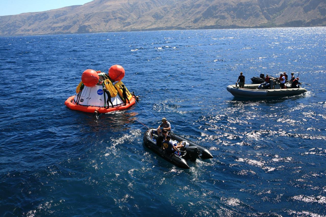 SAN DIEGO, Calif. – The Orion boilerplate test vehicle floats in the Pacific Ocean during Underway Recovery Test 4A. Orion was lowered into the water with a stationary crane from the USS Salvor, a safeguard-class rescue and salvage ship. Nearby, U.S. Navy personnel in a Zodiac boat, left, and a rigid hull inflatable boat practice procedures to tether and retrieve the test vehicle. U.S. Navy divers are standing on the flotation collar that has been placed around the test vehicle. NASA, Lockheed Martin and the U.S. Navy are conducting crane recovery tests to prepare for recovery of the Orion crew module on its return from a deep space mission. The underway recovery test will allow the teams to demonstrate and evaluate the recovery processes, procedures, new hardware and personnel in open waters.    The Ground Systems Development and Operations Program is conducting the underway recovery test. Orion is the exploration spacecraft designed to carry astronauts to destinations not yet explored by humans, including an asteroid and Mars. It will have emergency abort capability, sustain the crew during space travel and provide safe re-entry from deep space return velocities. The first unpiloted test flight of the Orion is scheduled to launch in December 2014 atop a United Launch Alliance Delta IV Heavy rocket and in 2018 on NASA’s Space Launch System rocket. For more information, visit http://www.nasa.gov/orion. Photo credit: Kim Shiflett