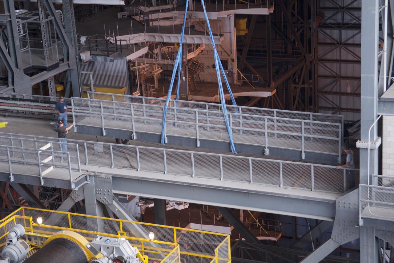 CAPE CANAVERAL, Fla. – Inside the Vehicle Assembly Building, or VAB, at NASA's Kennedy Space Center in Florida, workers monitor the progress as a crane lifts up a portion of the catwalk on the east side of Level 16. The catwalk is being removed to allow room for the removal of the 175-ton crane that is situated above the transfer aisle. The crane will be lowered to the floor to perform upgrades to its 45-year-old controls in order to improve reliability, precision and safety. The Ground Systems Development and Operations Program is overseeing upgrades and modifications to the VAB. The crane will be upgraded so that it can support lifting needs for NASA and other exploration vehicles, including the agency's Space Launch System and Orion spacecraft. Photo credit: NASA/Jim Grossmann