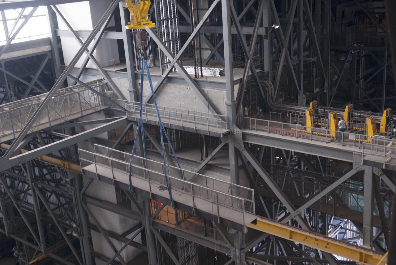 CAPE CANAVERAL, Fla. – Inside the Vehicle Assembly Building, or VAB, at NASA's Kennedy Space Center in Florida, a portion of the catwalk on the west side of Level 16 has been removed by crane and is being moved over the east side for storage. The catwalk was removed to allow room for the removal of the 175-ton crane that is situated above the transfer aisle. The crane will be lowered to the floor to perform upgrades to its 45-year-old controls in order to improve reliability, precision and safety. The Ground Systems Development and Operations Program is overseeing upgrades and modifications to the VAB. The crane will be upgraded so that it can support lifting needs for NASA and other exploration vehicles, including the agency's Space Launch System and Orion spacecraft. Photo credit: NASA/Jim Grossmann