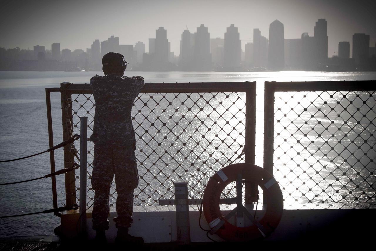 SAN DIEGO, Calif. – A member of the U.S. Navy watches the San Diego skyline from the deck of the USS Anchorage as the ship departs Naval Base San Diego on the first day of Orion Underway Recovery Test 3. The ship is heading out to sea, off the coast of San Diego, in search of conditions to support test needs for a full dress rehearsal of recovery operations. NASA, Lockheed Martin and U.S. Navy personnel will conduct tests in the Pacific Ocean to prepare for recovery of the Orion crew module on its return from a deep space mission. The test will allow the teams to demonstrate and evaluate the recovery processes, procedures, hardware and personnel in open waters.    The Ground Systems Development and Operations Program is conducting the underway recovery tests. Orion is the exploration spacecraft designed to carry astronauts to destinations not yet explored by humans, including an asteroid and Mars. It will have emergency abort capability, sustain the crew during space travel and provide safe re-entry from deep space return velocities. The first unpiloted test flight of Orion is scheduled to launch in 2014 atop a United Launch Alliance Delta IV Heavy rocket and in 2018 on NASA’s Space Launch System rocket. For more information, visit http://www.nasa.gov/orion. Photo credit: NASA/Cory Huston
