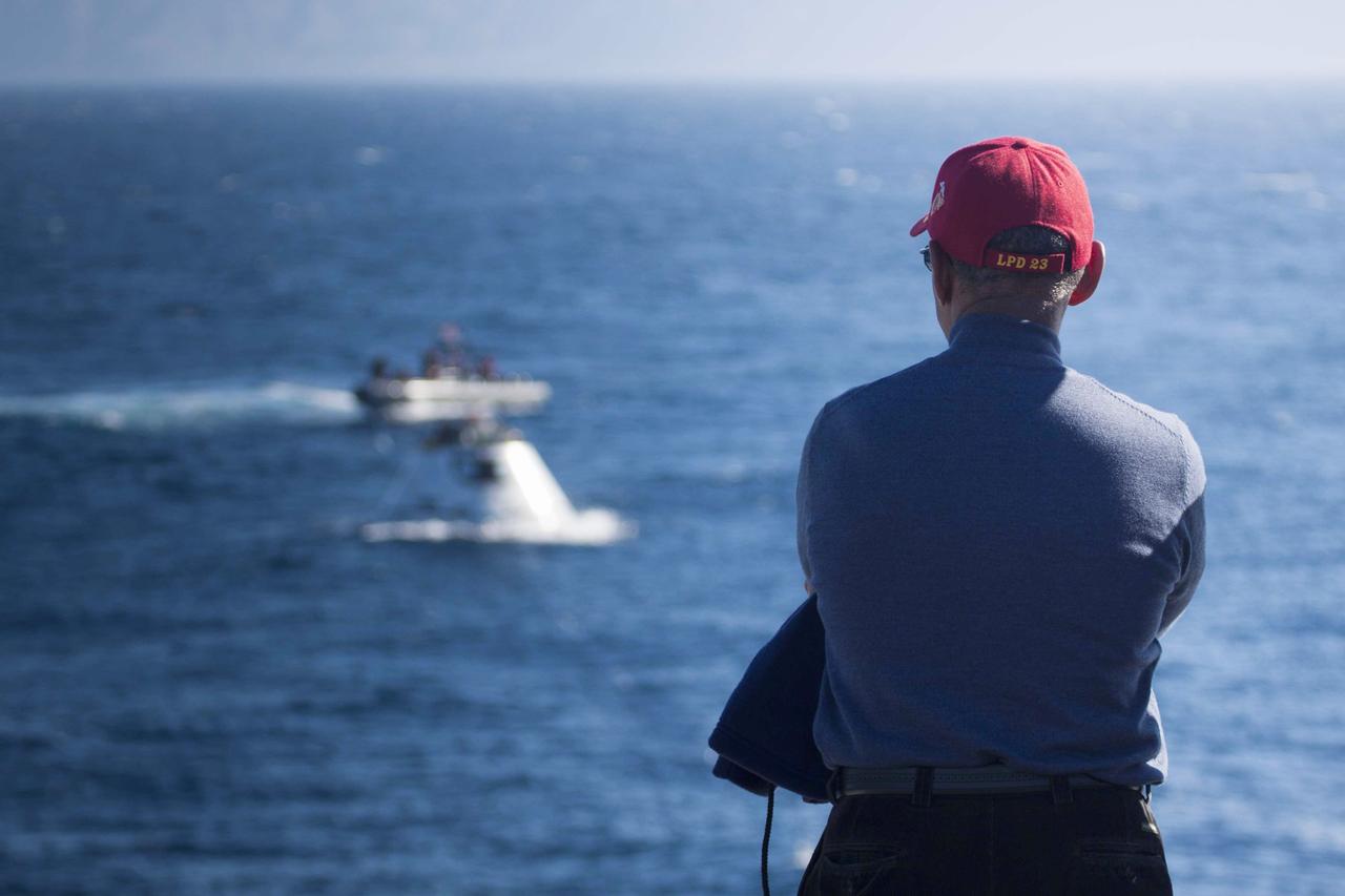 SAN DIEGO, Calif. – NASA Administrator Charlie Bolden stands on the deck of the USS Anchorage on the first day of Orion Underway Recovery Test 3. The Orion boilerplate test vehicle floats in the Pacific Ocean with U.S. Navy divers in a rigid hull inflatable boat nearby. NASA, Lockheed Martin and U.S. Navy personnel are conducting a full dress rehearsal of recovery operations in the Pacific Ocean to prepare for recovery of the Orion crew module on its return from a deep space mission. The test will allow the teams to demonstrate and evaluate the recovery processes, procedures, hardware and personnel in open waters.    The Ground Systems Development and Operations Program is conducting the underway recovery tests. Orion is the exploration spacecraft designed to carry astronauts to destinations not yet explored by humans, including an asteroid and Mars. It will have emergency abort capability, sustain the crew during space travel and provide safe re-entry from deep space return velocities. The first unpiloted test flight of Orion is scheduled to launch in 2014 atop a United Launch Alliance Delta IV Heavy rocket and in 2018 on NASA’s Space Launch System rocket. For more information, visit http://www.nasa.gov/orion. Photo credit: NASA/Cory Huston
