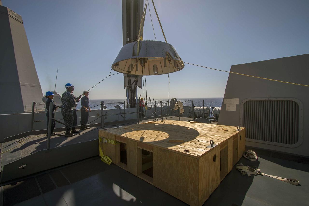 SAN DIEGO, Calif. – A mock-up of the Orion forward bay cover is being lifted by crane on the USS Anchorage during the second day of Orion Underway Recovery Test 3 in the Pacific Ocean. NASA, Lockheed Martin and U.S. Navy personnel are conducting the recovery test using the Orion boilerplate test vehicle and mock-up forward bay cover to prepare for recovery of the Orion crew module on its return from a deep space mission. The test allows the teams to demonstrate and evaluate the recovery processes, procedures, hardware and personnel in open waters. The Ground Systems Development and Operations Program is conducting the underway recovery tests. Orion is the exploration spacecraft designed to carry astronauts to destinations not yet explored by humans, including an asteroid and Mars. It will have emergency abort capability, sustain the crew during space travel and provide safe re-entry from deep space return velocities. The first unpiloted test flight of Orion is scheduled to launch in 2014 atop a United Launch Alliance Delta IV Heavy rocket and in 2018 on NASA’s Space Launch System rocket. For more information, visit http://www.nasa.gov/orion. Photo credit: NASA/Cory Huston