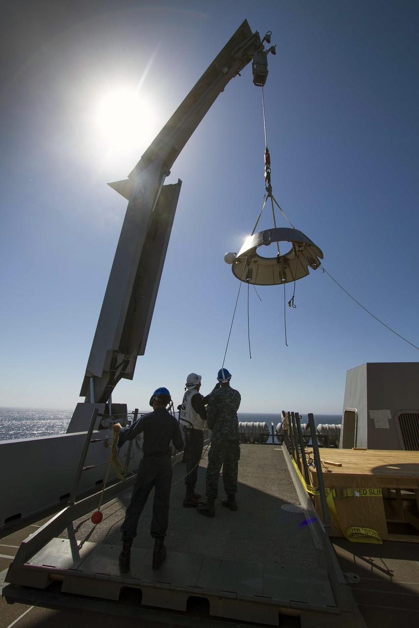SAN DIEGO, Calif. – A mock-up of the Orion forward bay cover is being lifted by crane on the USS Anchorage during the second day of Orion Underway Recovery Test 3 in the Pacific Ocean. NASA, Lockheed Martin and U.S. Navy personnel are conducting the recovery test using the Orion boilerplate test vehicle and mock-up forward bay cover to prepare for recovery of the Orion crew module on its return from a deep space mission. The test allows the teams to demonstrate and evaluate the recovery processes, procedures, hardware and personnel in open waters.    The Ground Systems Development and Operations Program is conducting the underway recovery tests. Orion is the exploration spacecraft designed to carry astronauts to destinations not yet explored by humans, including an asteroid and Mars. It will have emergency abort capability, sustain the crew during space travel and provide safe re-entry from deep space return velocities. The first unpiloted test flight of Orion is scheduled to launch in 2014 atop a United Launch Alliance Delta IV Heavy rocket and in 2018 on NASA’s Space Launch System rocket. For more information, visit http://www.nasa.gov/orion. Photo credit: NASA/Cory Huston