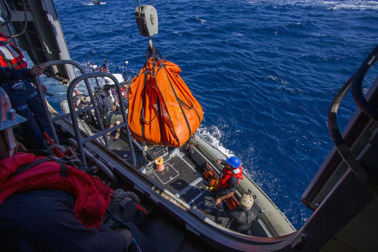 SAN DIEGO, Calif. – A crane lifts a mock-up of the Orion forward bay cover in its net from a boat docked near the well deck of the USS Anchorage during the second day of Orion Underway Recovery Test 3 in the Pacific Ocean. NASA, Lockheed Martin and U.S. Navy personnel are conducting the recovery test using the Orion boilerplate test vehicle and mock-up forward bay cover to prepare for recovery of the Orion crew module on its return from a deep space mission. The test allows the teams to demonstrate and evaluate the recovery processes, procedures, hardware and personnel in open waters. The Ground Systems Development and Operations Program is conducting the underway recovery tests. Orion is the exploration spacecraft designed to carry astronauts to destinations not yet explored by humans, including an asteroid and Mars. It will have emergency abort capability, sustain the crew during space travel and provide safe re-entry from deep space return velocities. The first unpiloted test flight of Orion is scheduled to launch in 2014 atop a United Launch Alliance Delta IV Heavy rocket and in 2018 on NASA’s Space Launch System rocket. For more information, visit http://www.nasa.gov/orion. Photo credit: NASA/Cory Huston