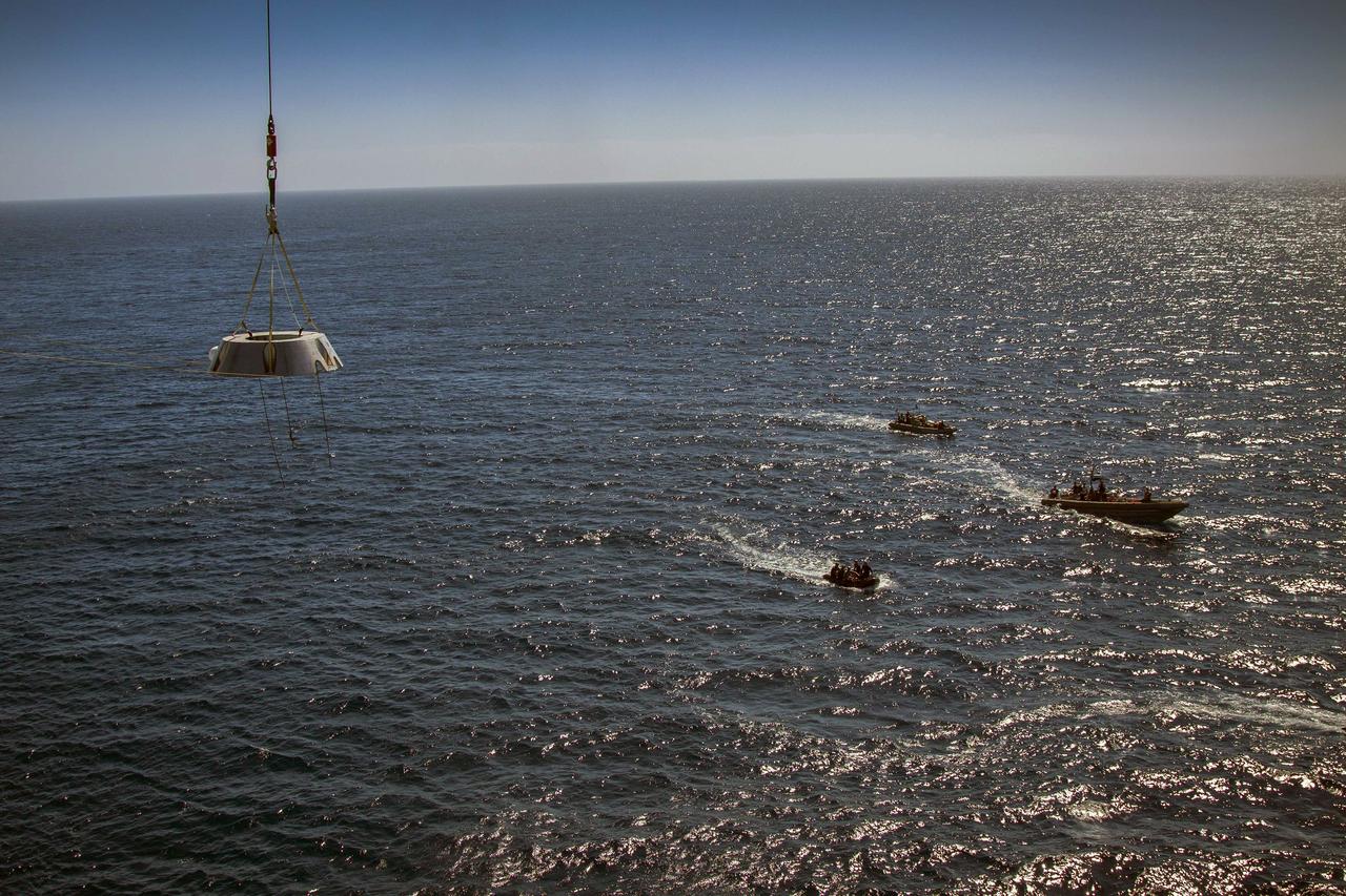 SAN DIEGO, Calif. – A mock-up of the Orion forward bay cover is lowered by crane from the USS Anchorage into the water during the second day of Orion Underway Recovery Test 3 in the Pacific Ocean. Nearby, U.S. navy divers in two Zodiac boats and other team members in a rigid hull inflatable boat, wait to practice recovery procedures. NASA, Lockheed Martin and U.S. Navy personnel are conducting the recovery test using the Orion boilerplate test vehicle and mock-up forward bay cover to prepare for recovery of the Orion crew module on its return from a deep space mission. The test allows the teams to demonstrate and evaluate the recovery processes, procedures, hardware and personnel in open waters. The Ground Systems Development and Operations Program is conducting the underway recovery tests. Orion is the exploration spacecraft designed to carry astronauts to destinations not yet explored by humans, including an asteroid and Mars. It will have emergency abort capability, sustain the crew during space travel and provide safe re-entry from deep space return velocities. The first unpiloted test flight of Orion is scheduled to launch in 2014 atop a United Launch Alliance Delta IV Heavy rocket and in 2018 on NASA’s Space Launch System rocket. For more information, visit http://www.nasa.gov/orion. Photo credit: NASA/Cory Huston