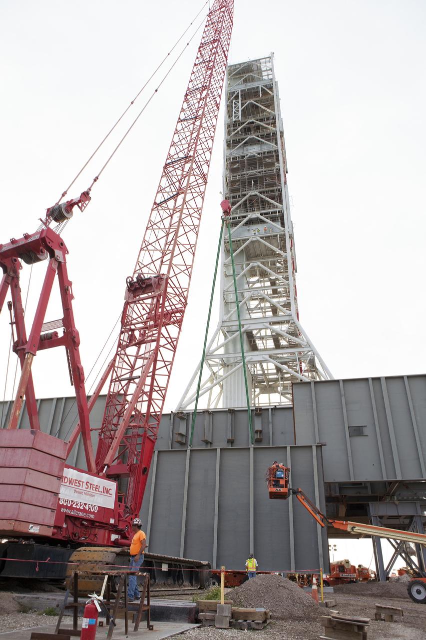 CAPE CANAVERAL, Fla. – A crane is used to lift the final large steel beam for installation on the base of the Mobile Launcher, or ML, at the Mobile Launcher Park Site at NASA’s Kennedy Space Center in Florida. The ML is being modified and strengthened to accommodate the weight, size and thrust at launch of NASA's Space Launch System, or SLS, and Orion spacecraft.    In 2013, the agency awarded a contract to J.P. Donovan Construction Inc. of Rockledge, Fla., to modify the ML, which is one of the key elements of ground support equipment that is being upgraded by the Ground Systems Development and Operations Program at Kennedy. The existing 24-foot exhaust hole is being enlarged and strengthened for the larger, heavier SLS rocket. The ML will carry the SLS rocket and Orion spacecraft to Launch Pad 39B for its first uncrewed mission, Exploration Mission-1, in 2018. Photo credit: NASA/Daniel Casper